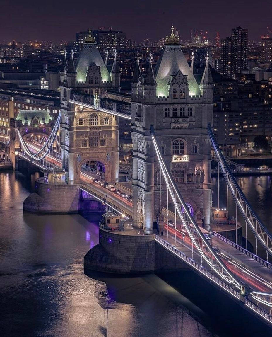 英國倫敦塔橋夜景 壁紙 — 倫敦的塔橋在夜晚閃耀著溫暖的燈光，倒映在下面的泰晤士河上。