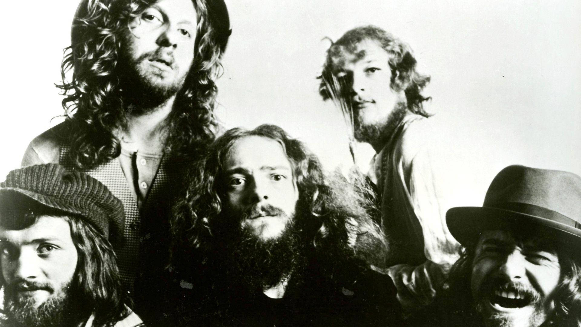 英國前衛搖滾樂隊 Jethro Tull 1972 年攝影棚拍攝 壁紙 — 五位留長髮、戴帽子的鬍鬚男在粗糙的黑白工作室肖像中緊密地擺姿勢。