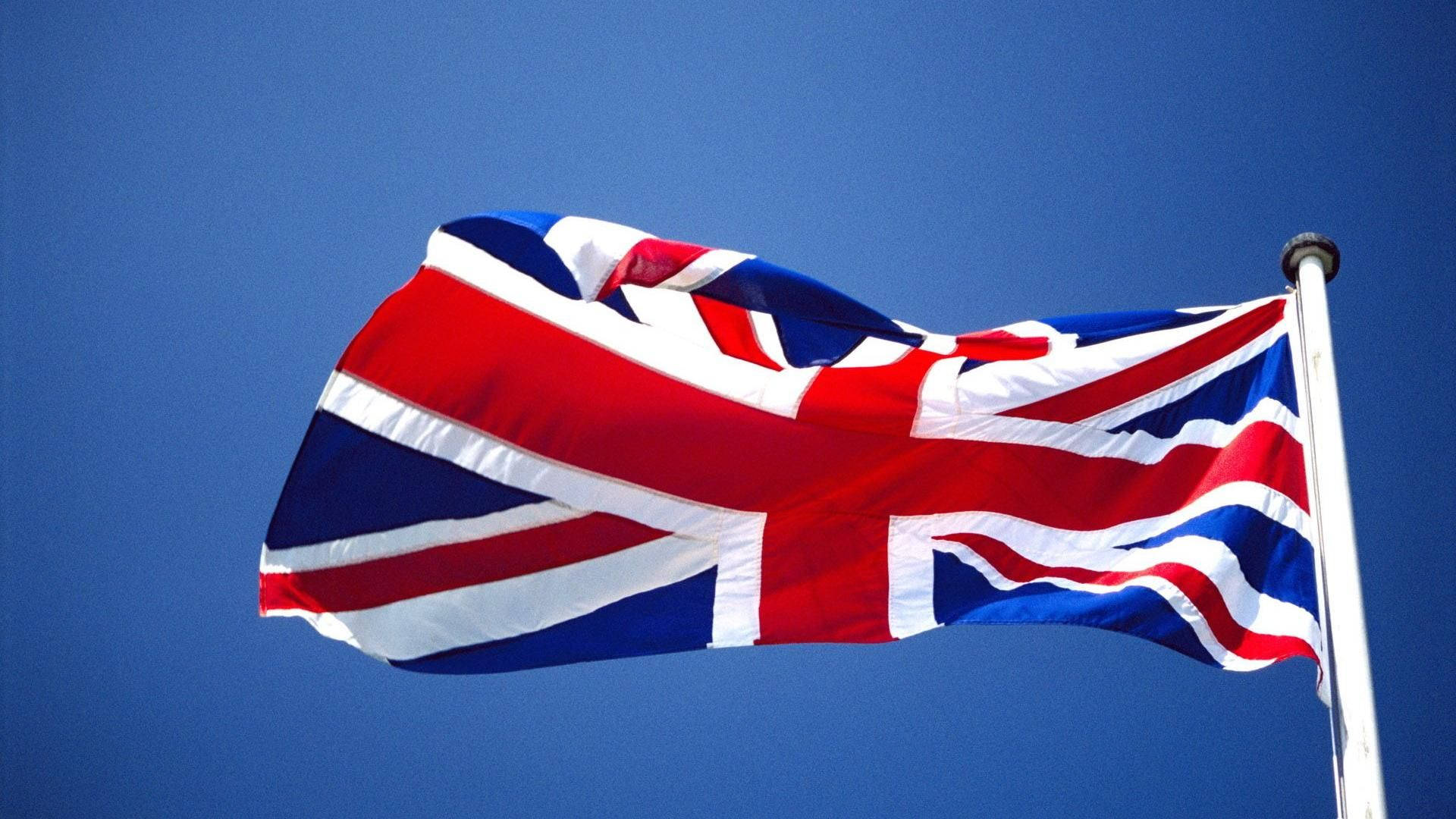 英國國旗旗桿 壁紙 — 英國國旗在晴朗的日子裡，在清澈的藍天下動態飄揚。