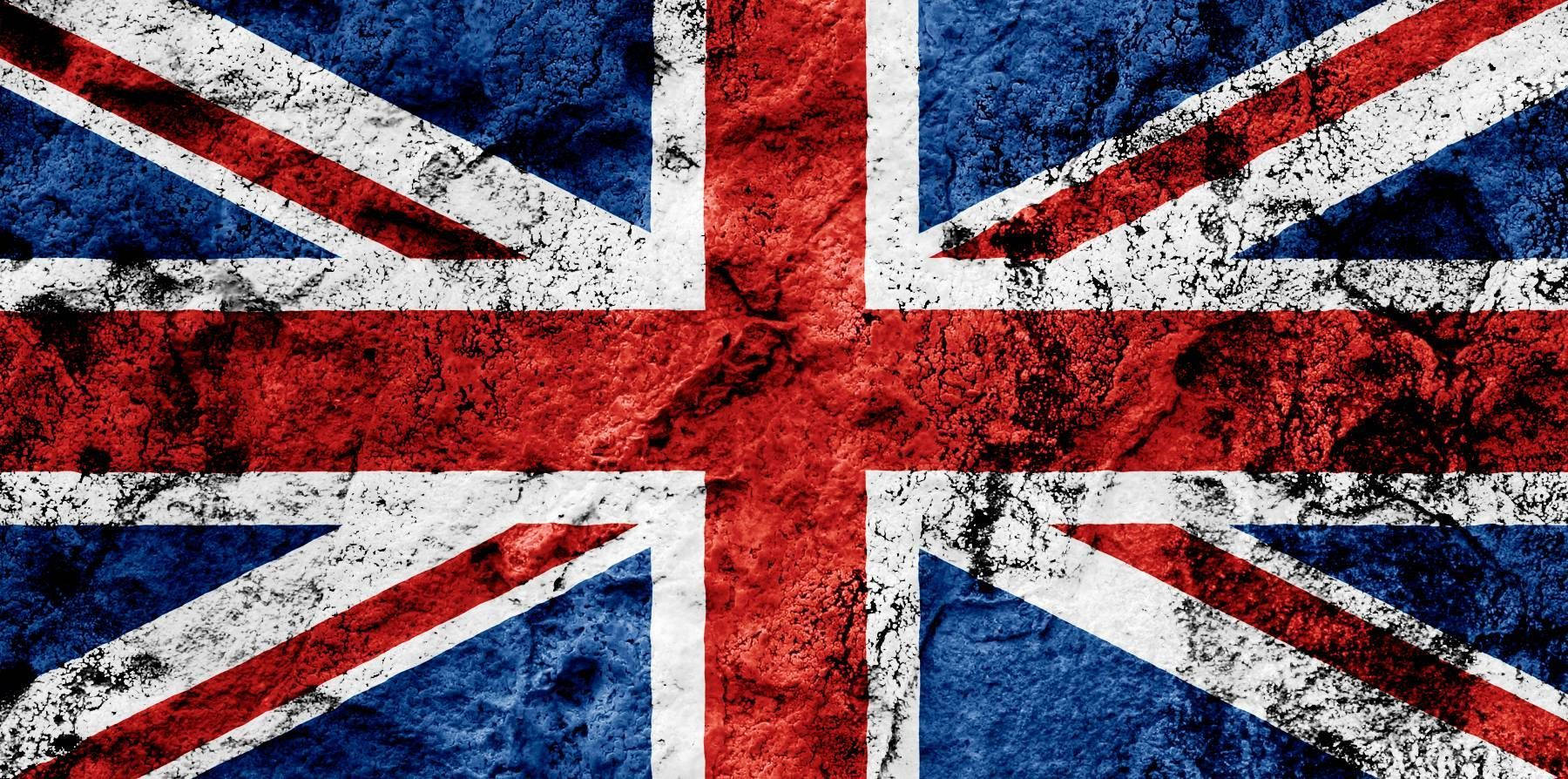 英國國旗覆蓋黑塵 壁紙 — 一面風化紋理的英國國旗，帶有鮮明的紅、白、藍色，顯示磨損痕跡。