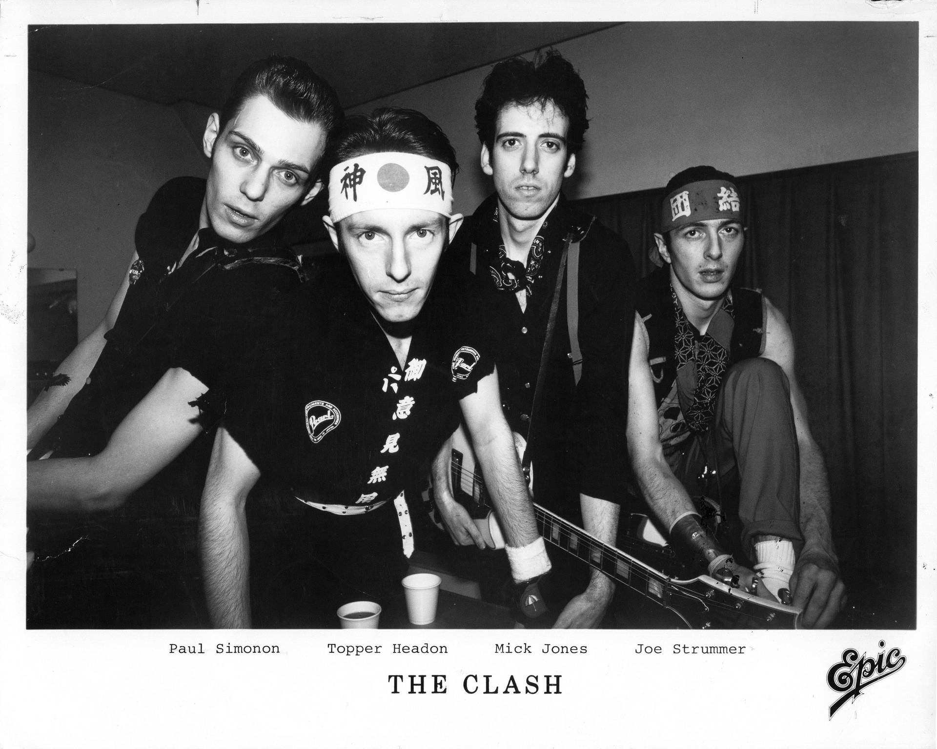 The Clash 樂隊成員身穿黑色龐克服裝，配戴日本頭帶和結他。