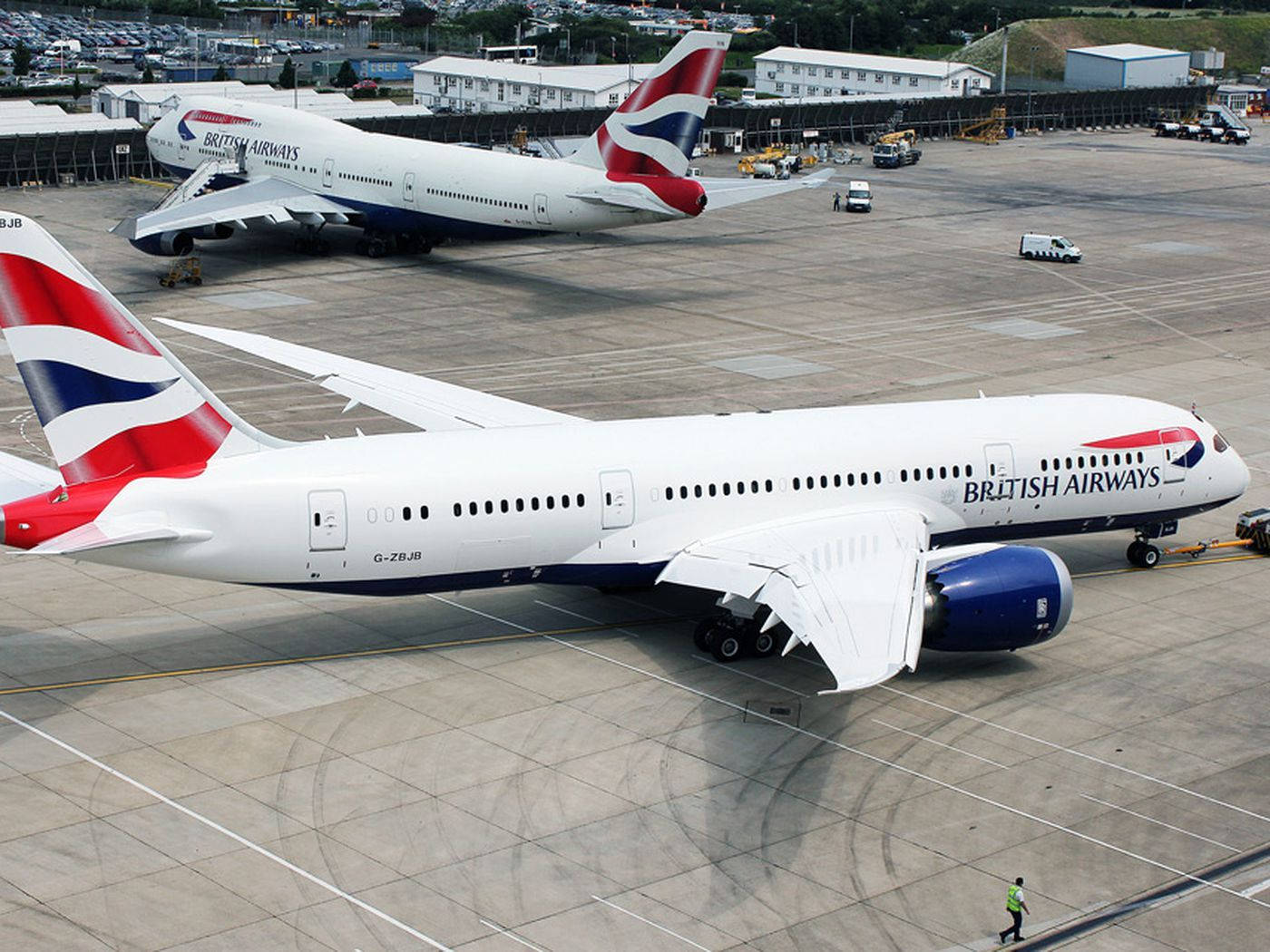 兩架英國航空飛機在機場停機坪上，有地勤人員和車輛。