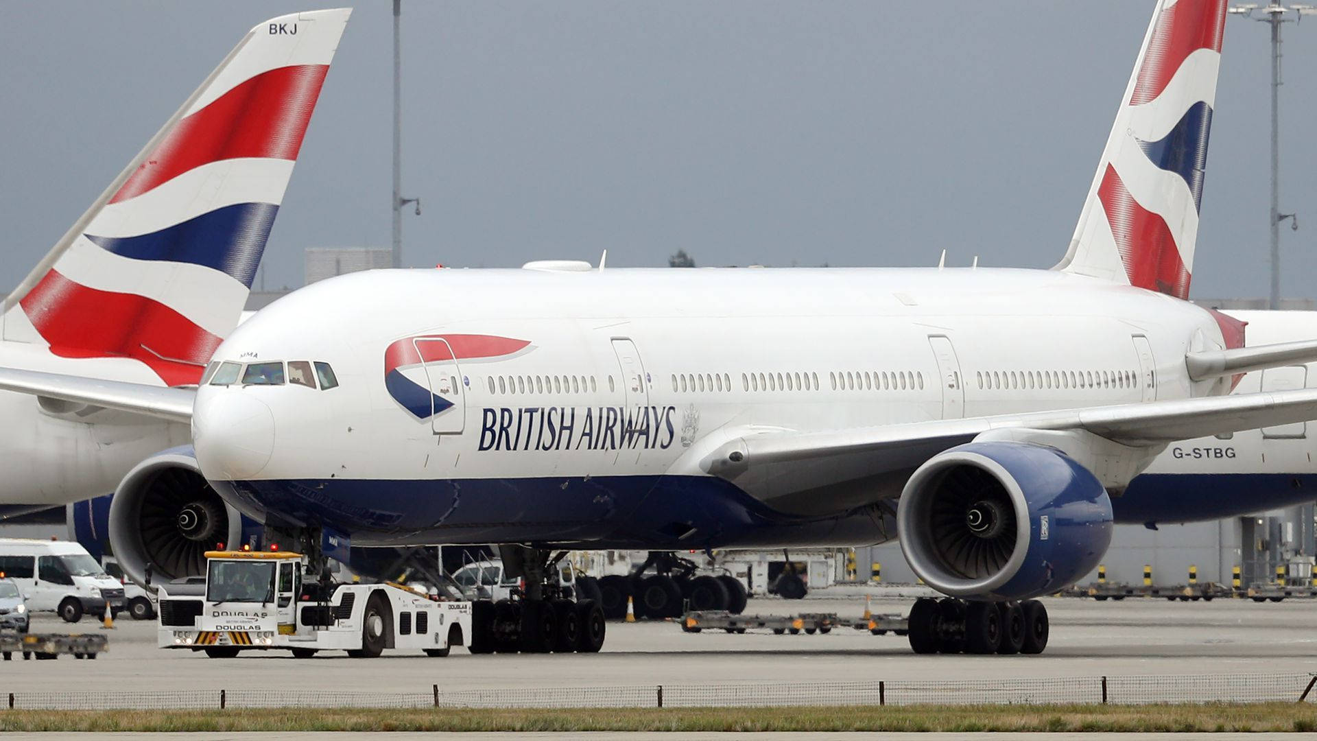 英國航空空中巴士A380在機場停機坪上，有地勤服務車輛。