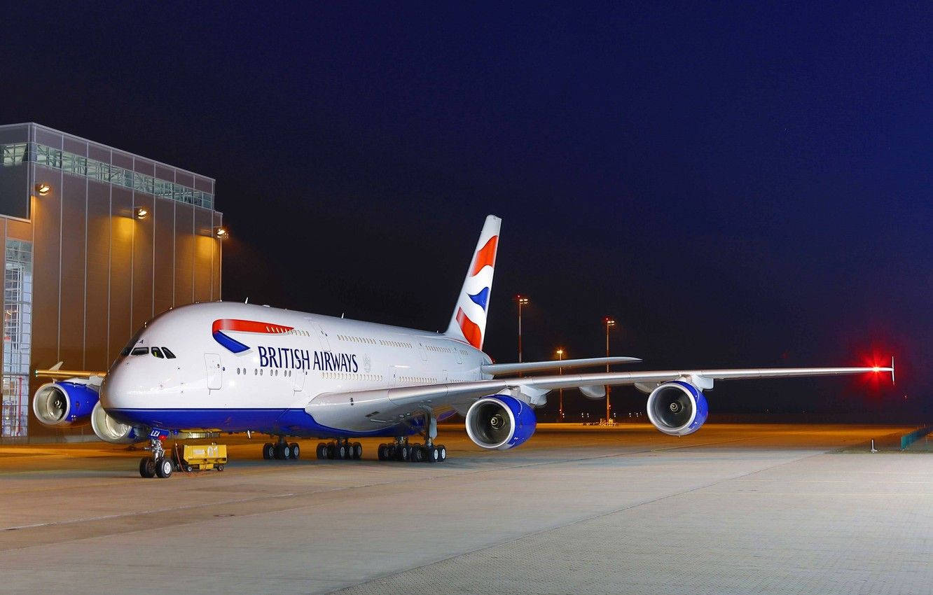 英國航空A380飛機在夜間停泊在機場停機坪上，靠近客運大樓。