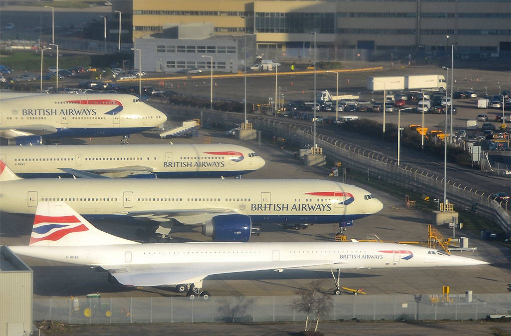 英國航空飛機停泊在機場停機坪，背景有客運大樓和地面車輛。