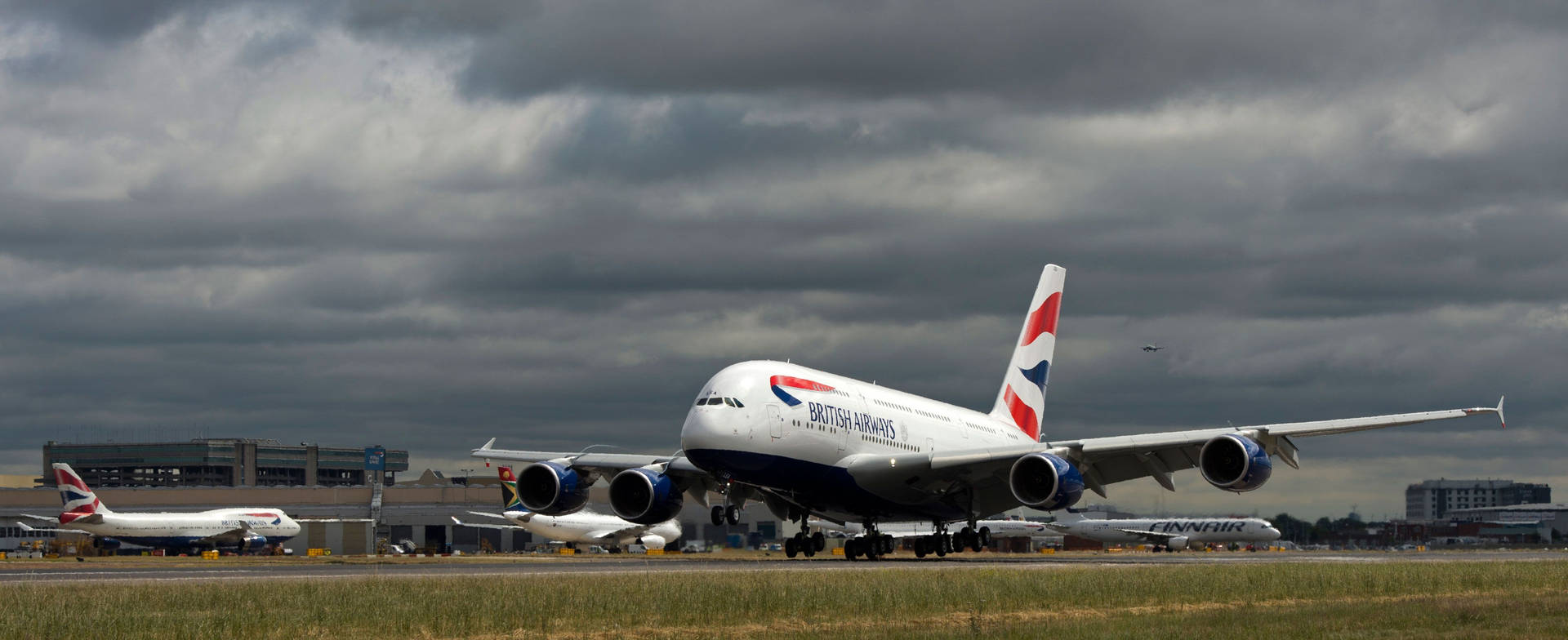 一架英國航空A380飛機在灰色雲層下於潮濕的跑道上滑行。