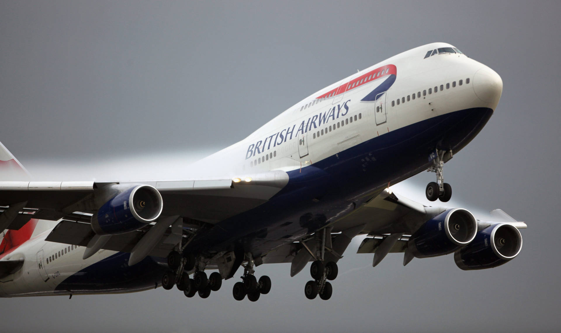 英國航空波音747飛機在灰色天空下放下起落架降落