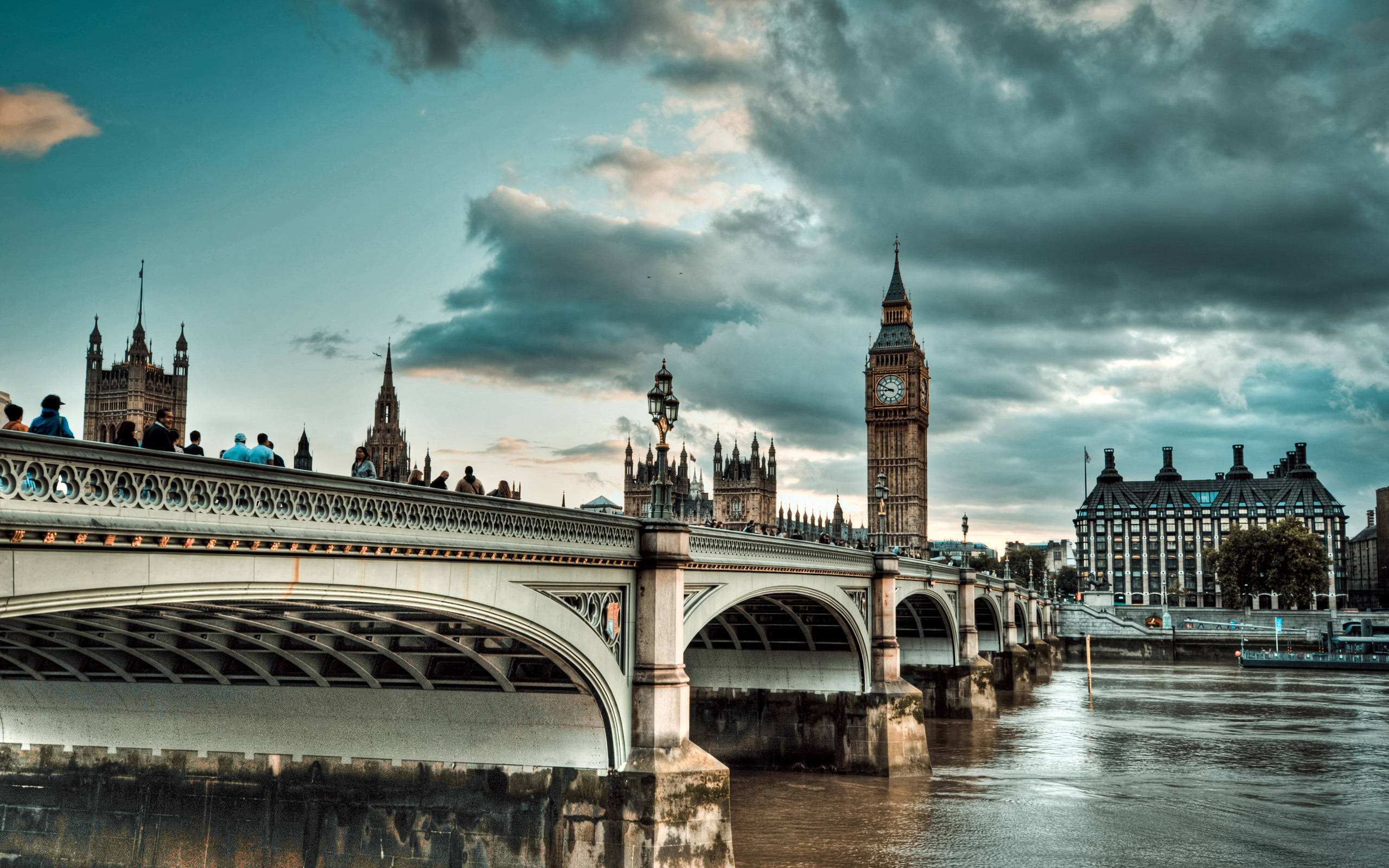 英國通往議會大廈的橋 壁紙 — 倫敦西敏橋在黃昏時的戲劇性景觀，大笨鐘和國會大廈在陰雲密布的天空下。