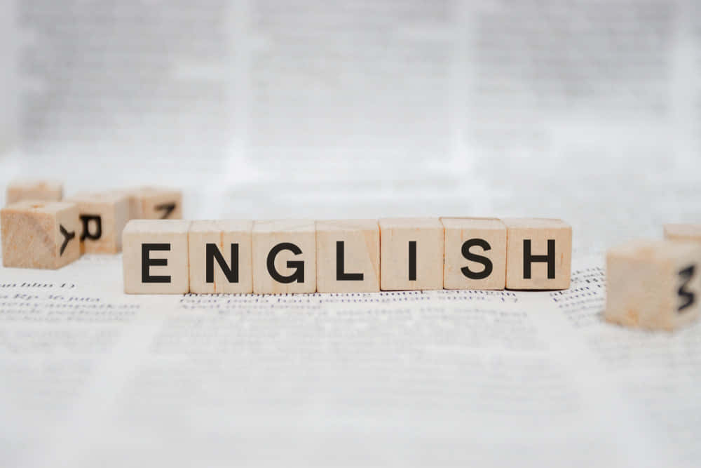 木製字母塊在報紙背景上拼出 English。 — 狂戰士 GIF 壁紙