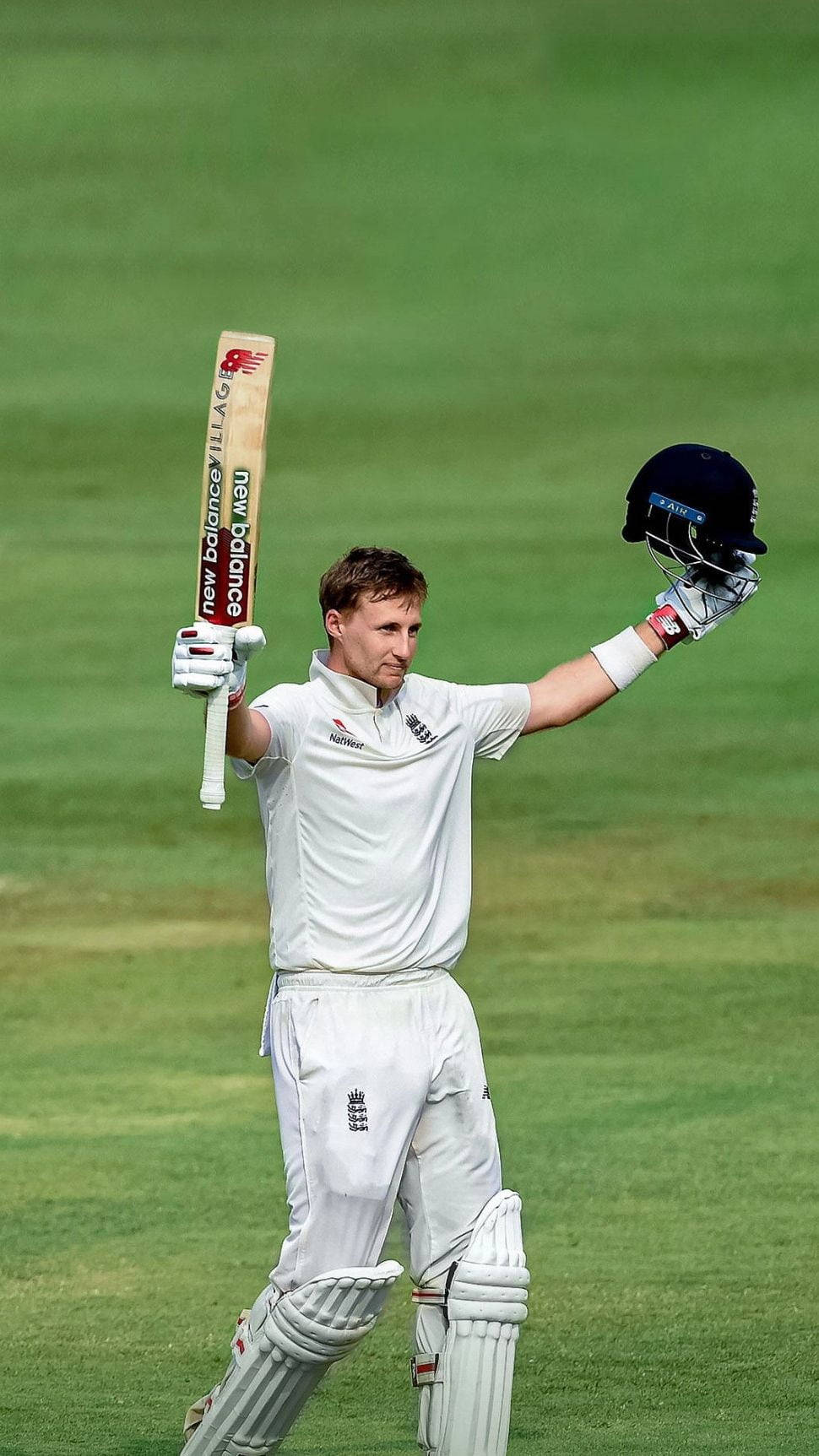 板球手在綠色球場上高舉球棒和頭盔慶祝。
