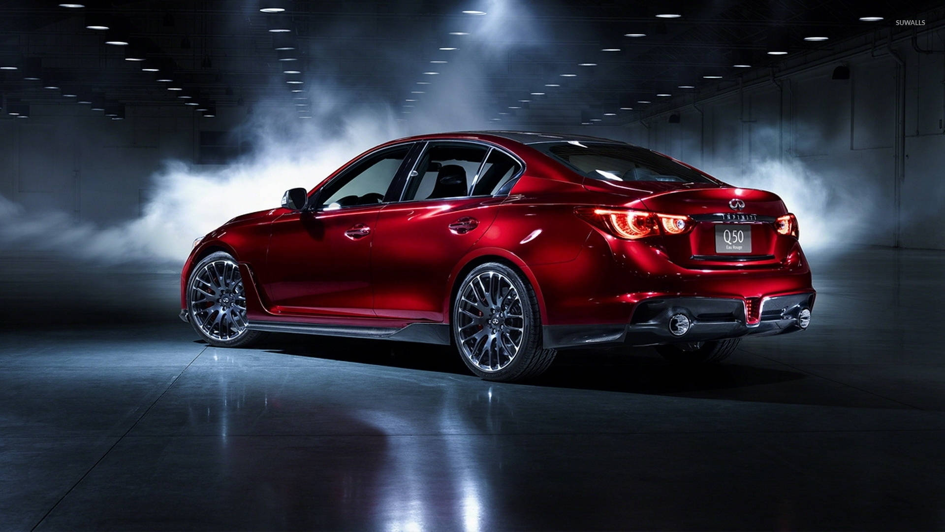 英菲尼迪 Q50 Eau Rouge 紅色款 壁紙 — 一輛光澤的紅色Infiniti Q50房車在黑暗的工業車庫中，於旋轉煙霧中在戲劇性的聚光燈下閃耀。