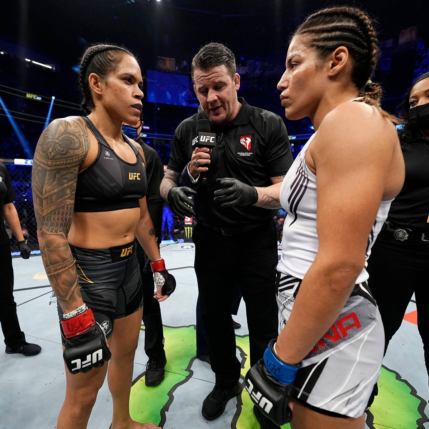 茱莉安娜·佩納與阿曼達·努內斯賽前 壁紙 — 兩位女性UFC拳手在八角籠中對峙，裁判在她們之間拿著麥克風。