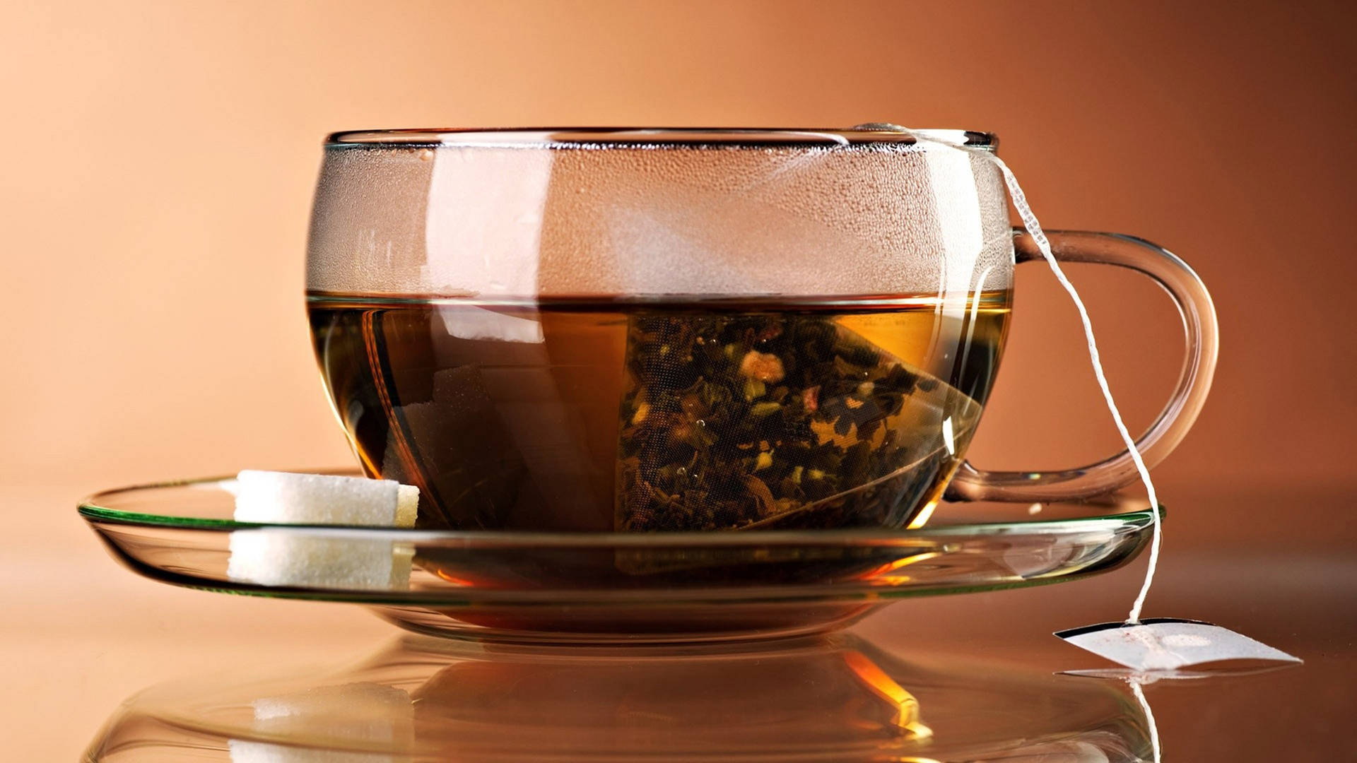 一個玻璃茶杯，內有茶包和方糖，放在茶托上。