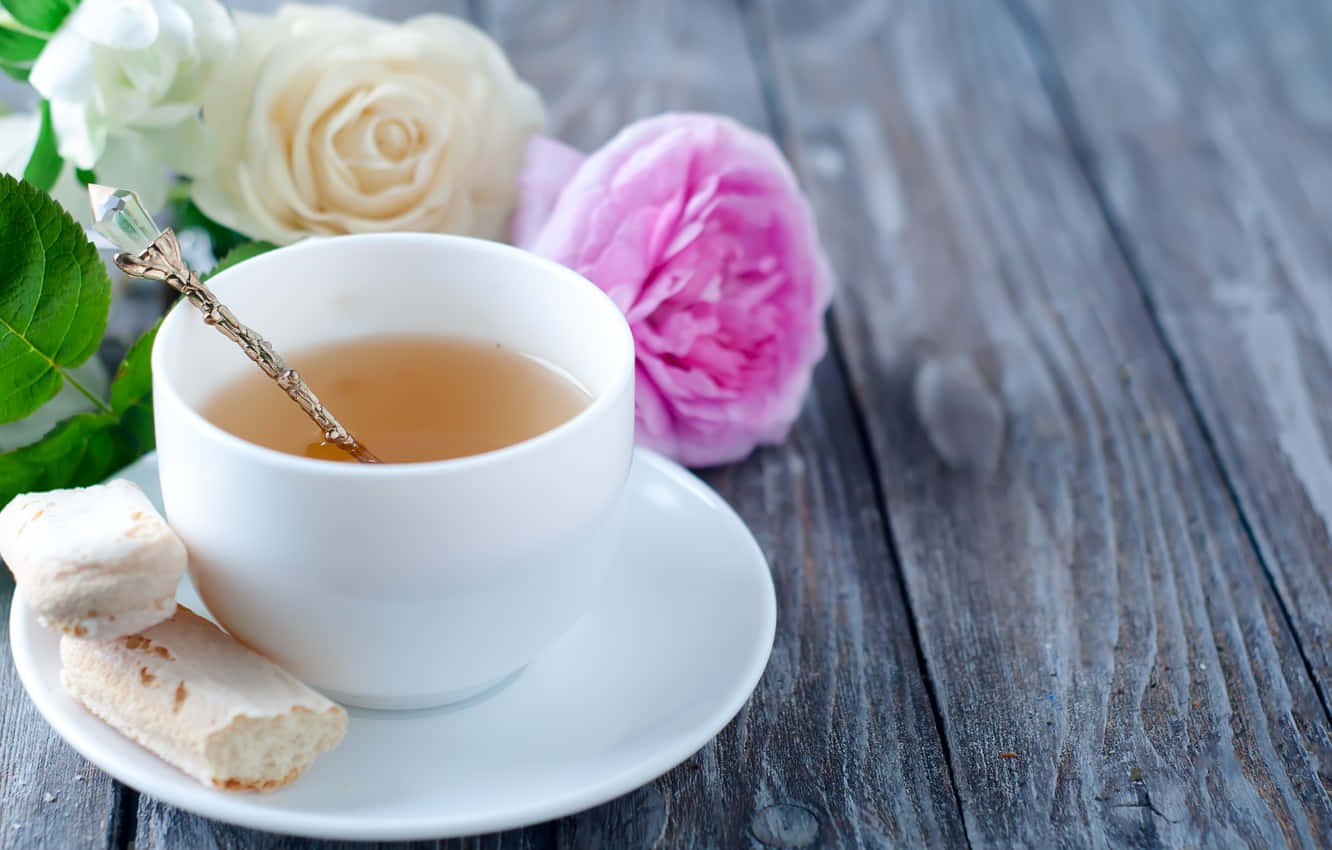 茶杯與麵包圖 壁紙 — 一隻白色茶杯盛載琥珀色茶和華麗的湯匙，放在碟子上，旁邊有粉紅和白色玫瑰及意大利脆餅在風化木上。