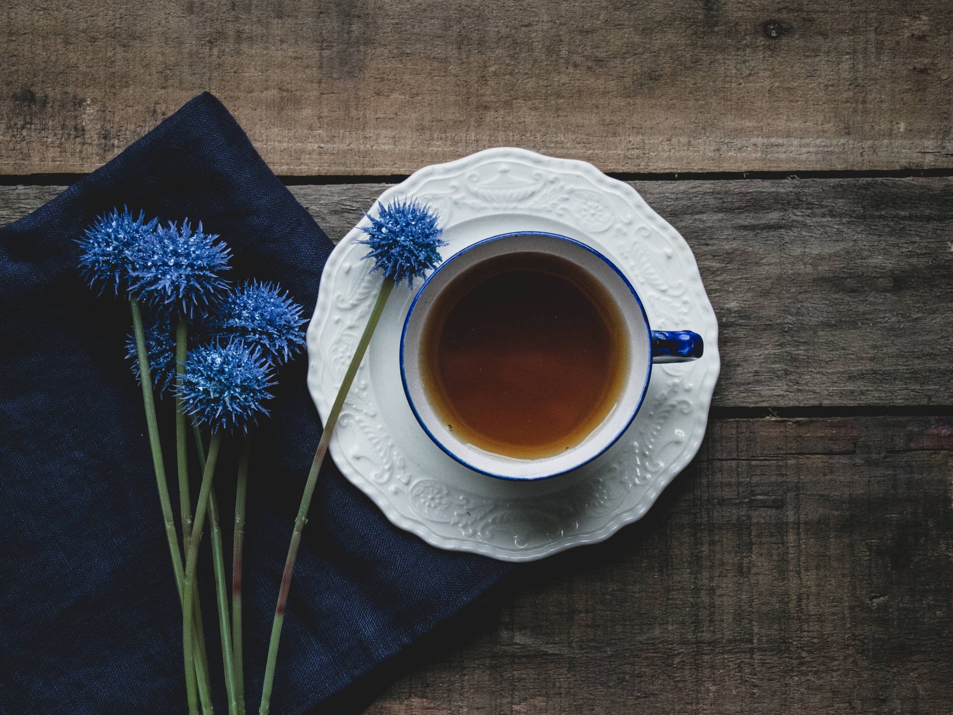 木桌上的一杯茶和藍色花朵。