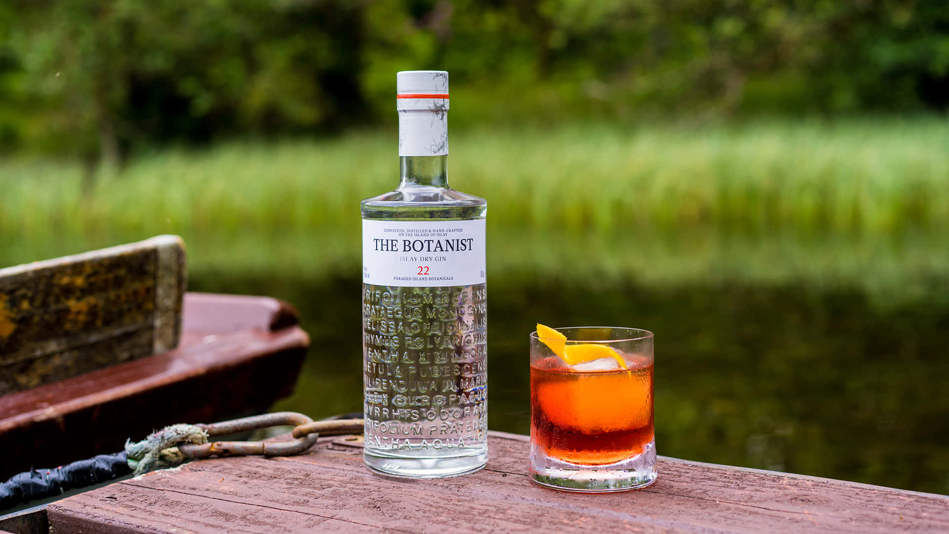 Botanist 氈酒瓶和雞尾酒在池塘邊的木碼頭上