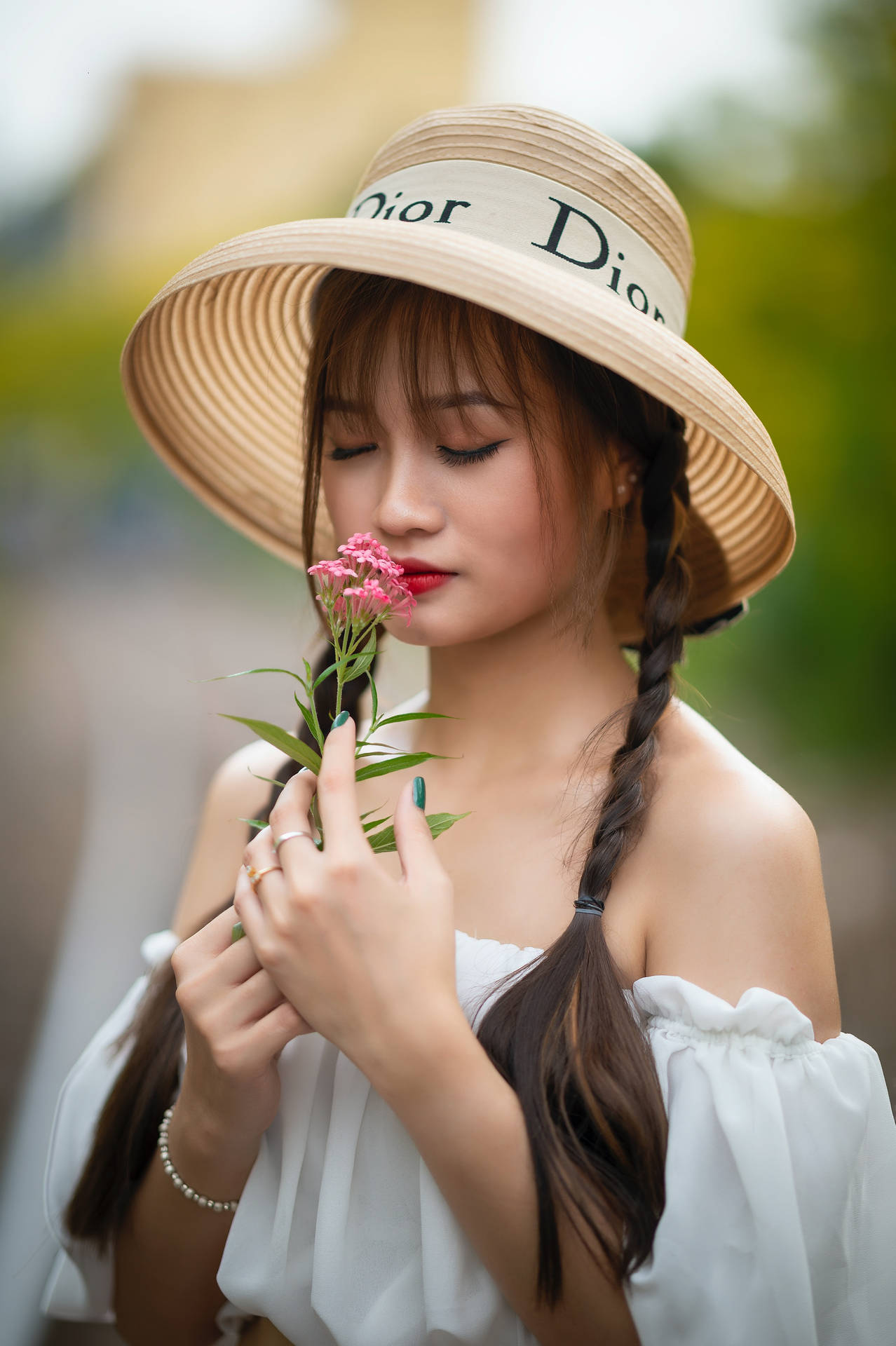 戴草帽的女性在戶外聞粉紅色的花