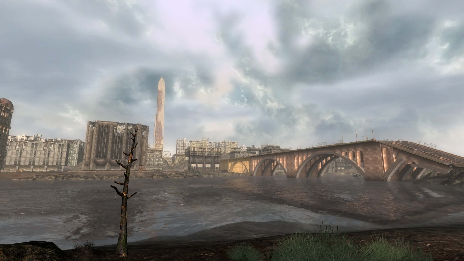 Fallout 4 The Capital Wasteland 桌布 壁紙 — 荒涼的河岸，有一座搖搖欲墜的橋樑和廢墟般的城市景觀，天空陰沉多雲。