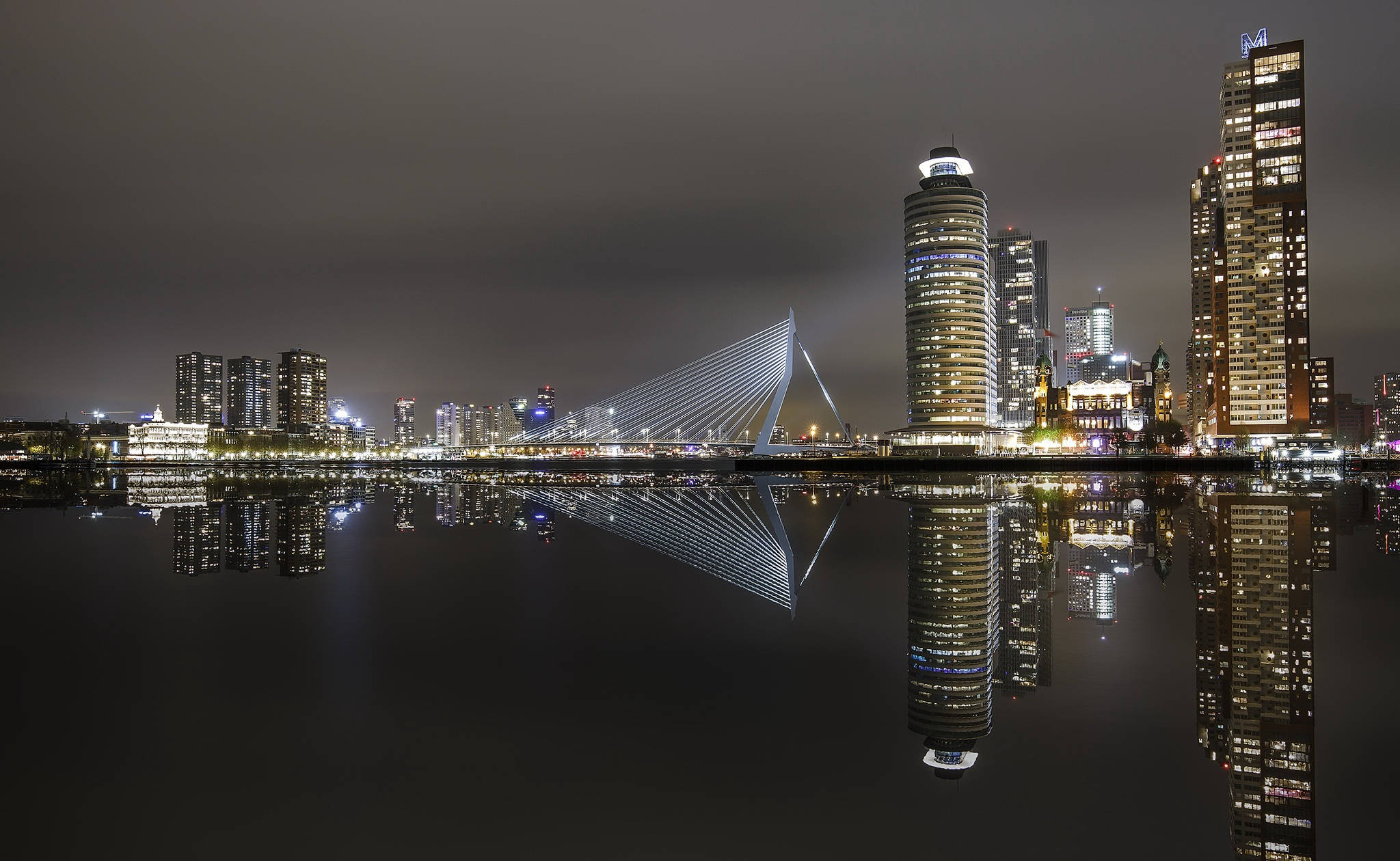 荷蘭鹿特丹夜景 壁紙 — 鹿特丹令人驚嘆的夜景，伊拉斯謨斯橋和摩天大樓完美倒映在平靜的水面上。