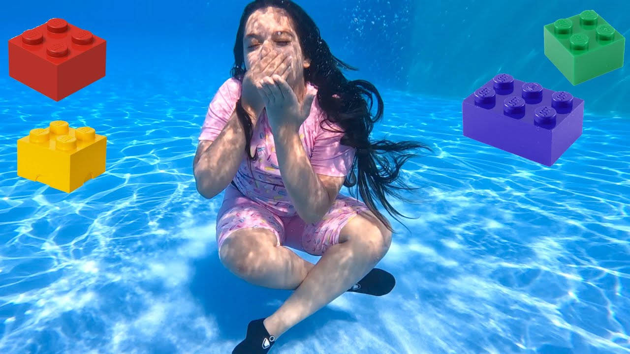 女孩在水底泳池中，巨大的LEGO積木漂浮在她周圍。