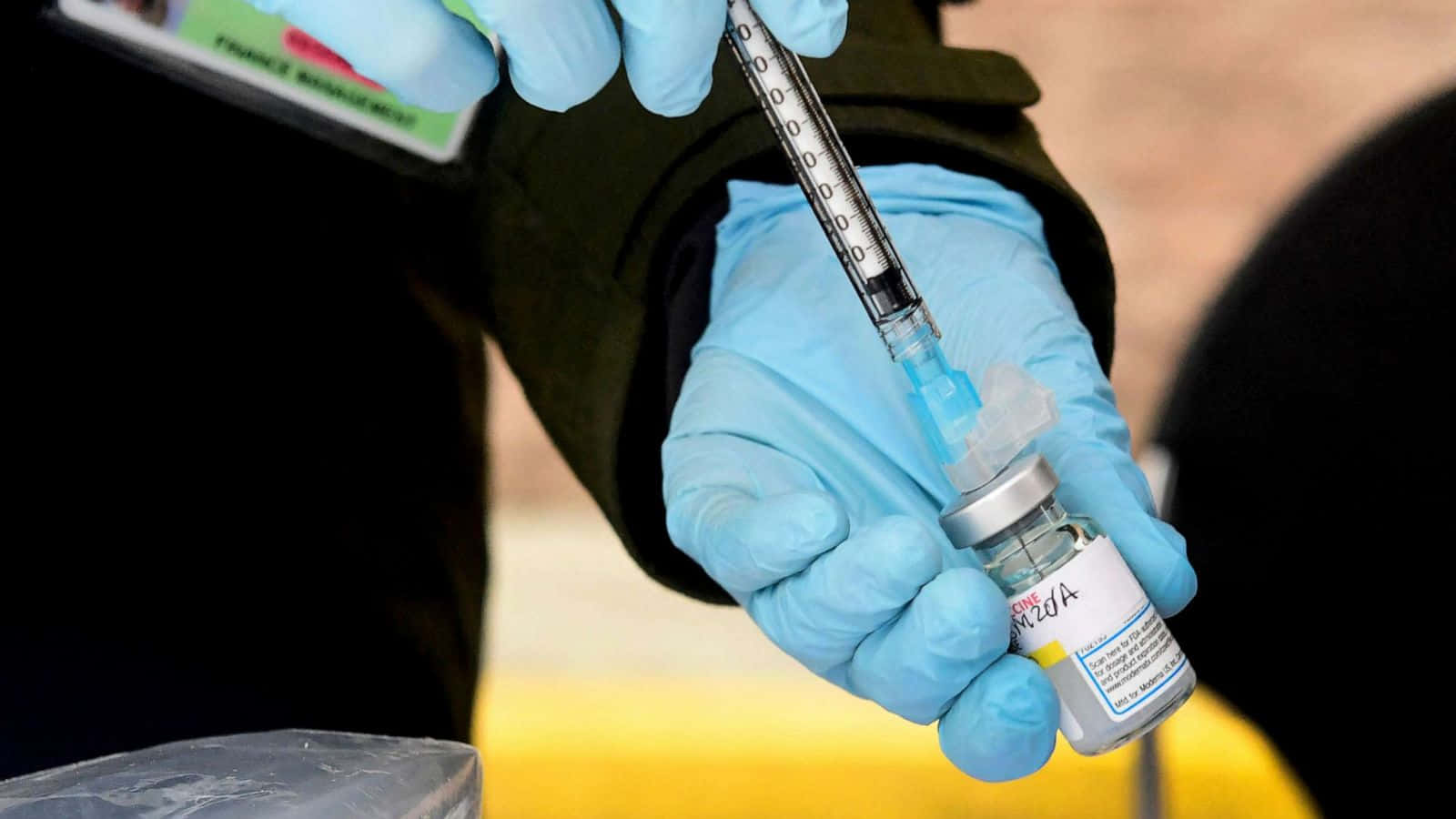 戴手套的醫護人員將疫苗吸入注射器