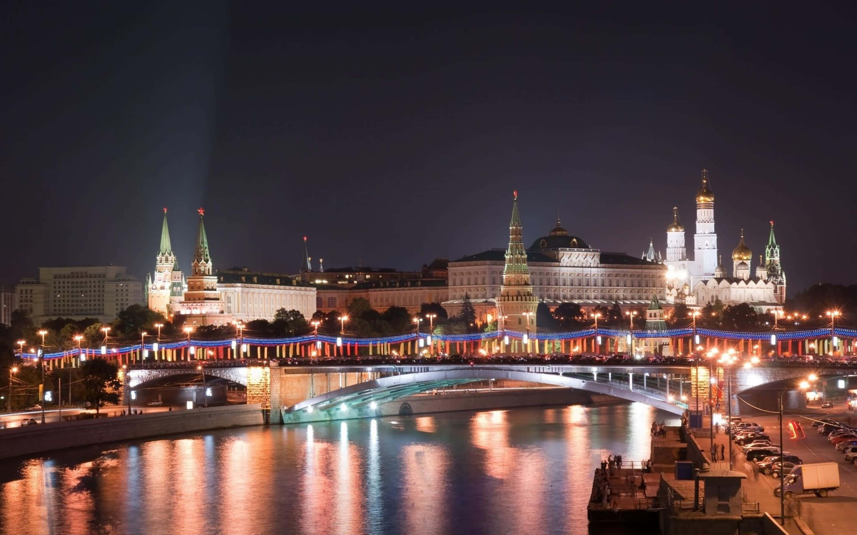 Russia 桌布 壁紙 — 莫斯科克里姆林宮的璀璨夜景，燈火通明的塔樓和尖頂倒映在下方閃爍的河流中。