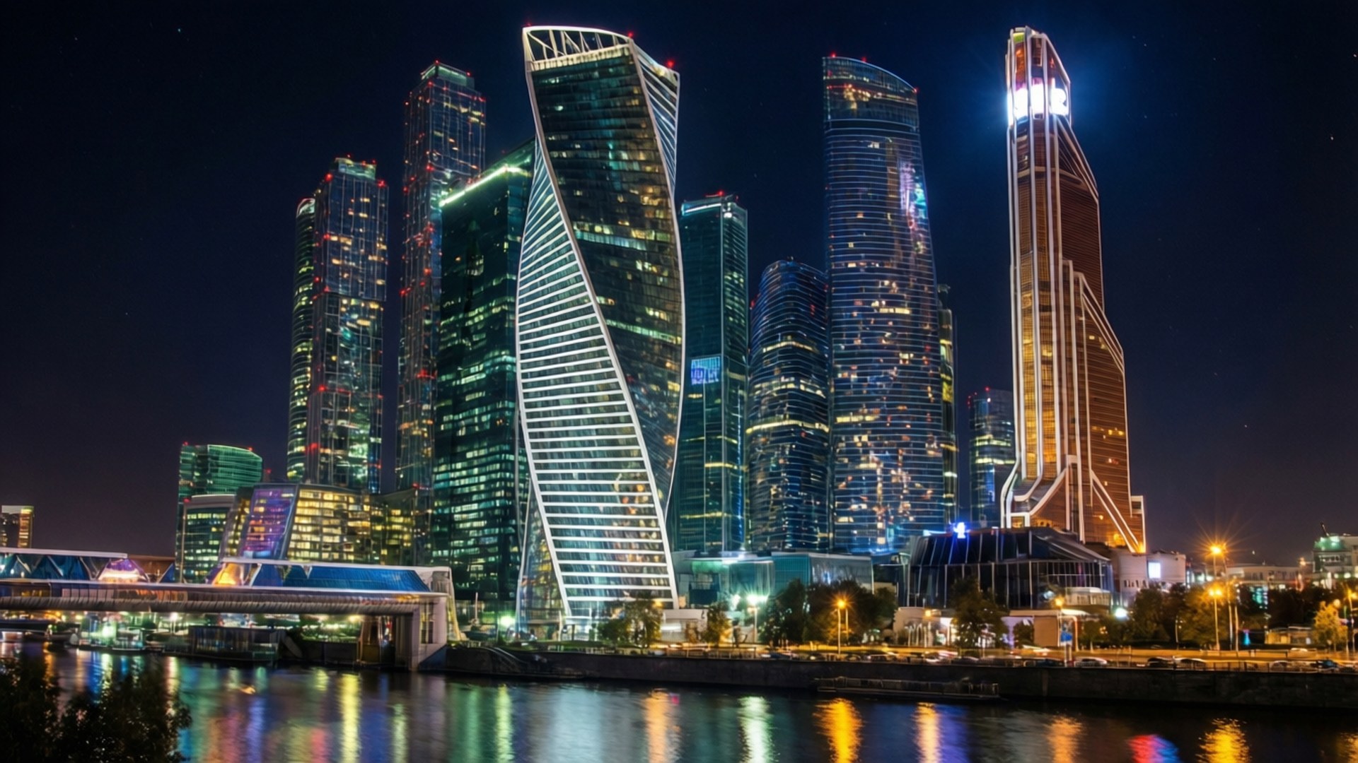 莫斯科城市夜景 壁紙 — 在黑暗的天空下，現代摩天大樓閃爍的窗戶倒映在平靜的河面上，構成迷人的夜景。