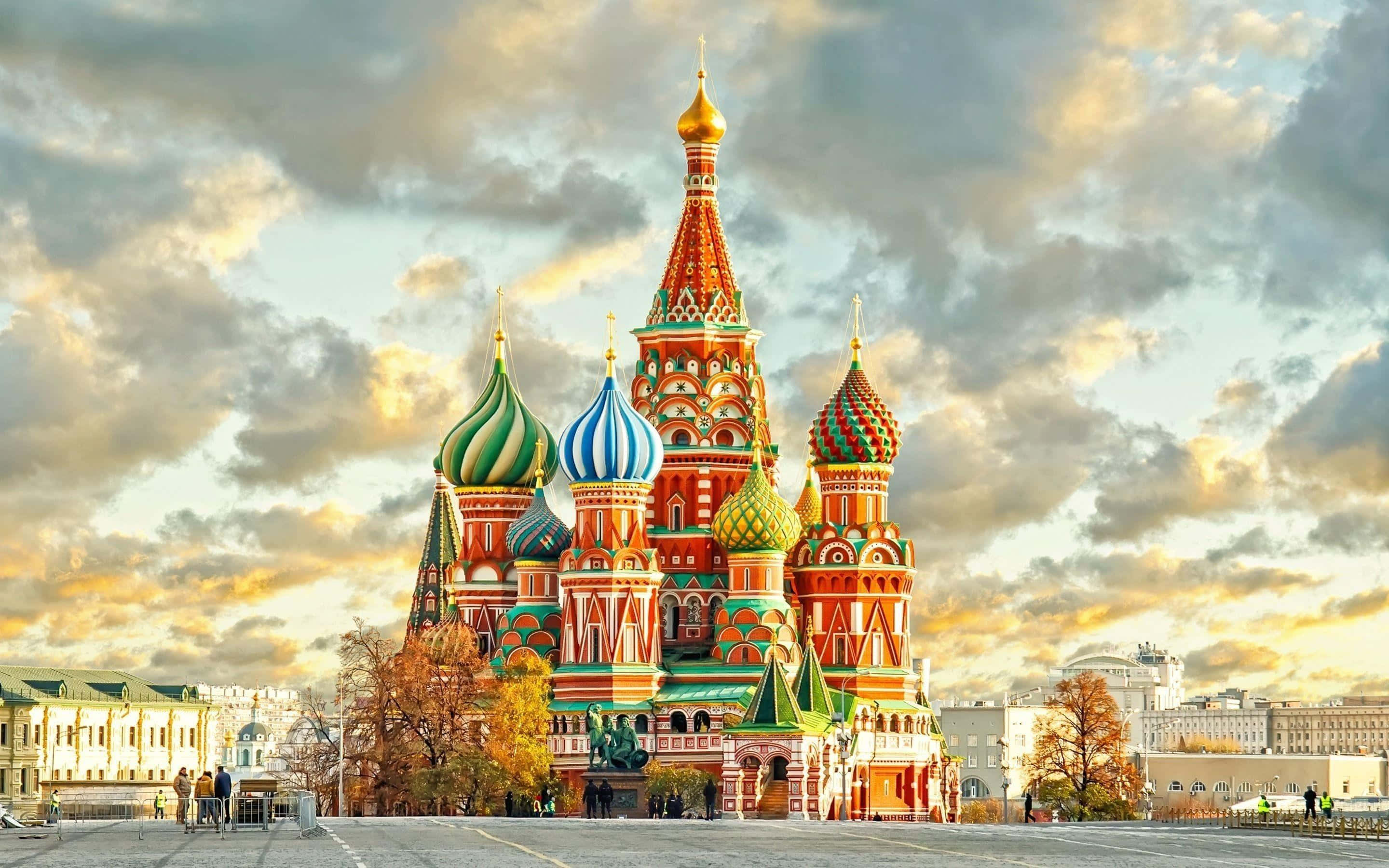 Russia 桌布 壁紙 — 莫斯科的聖瓦西里大教堂在戲劇性的日落天空下閃耀，伴隨著金色的雲彩和秋天的樹木。