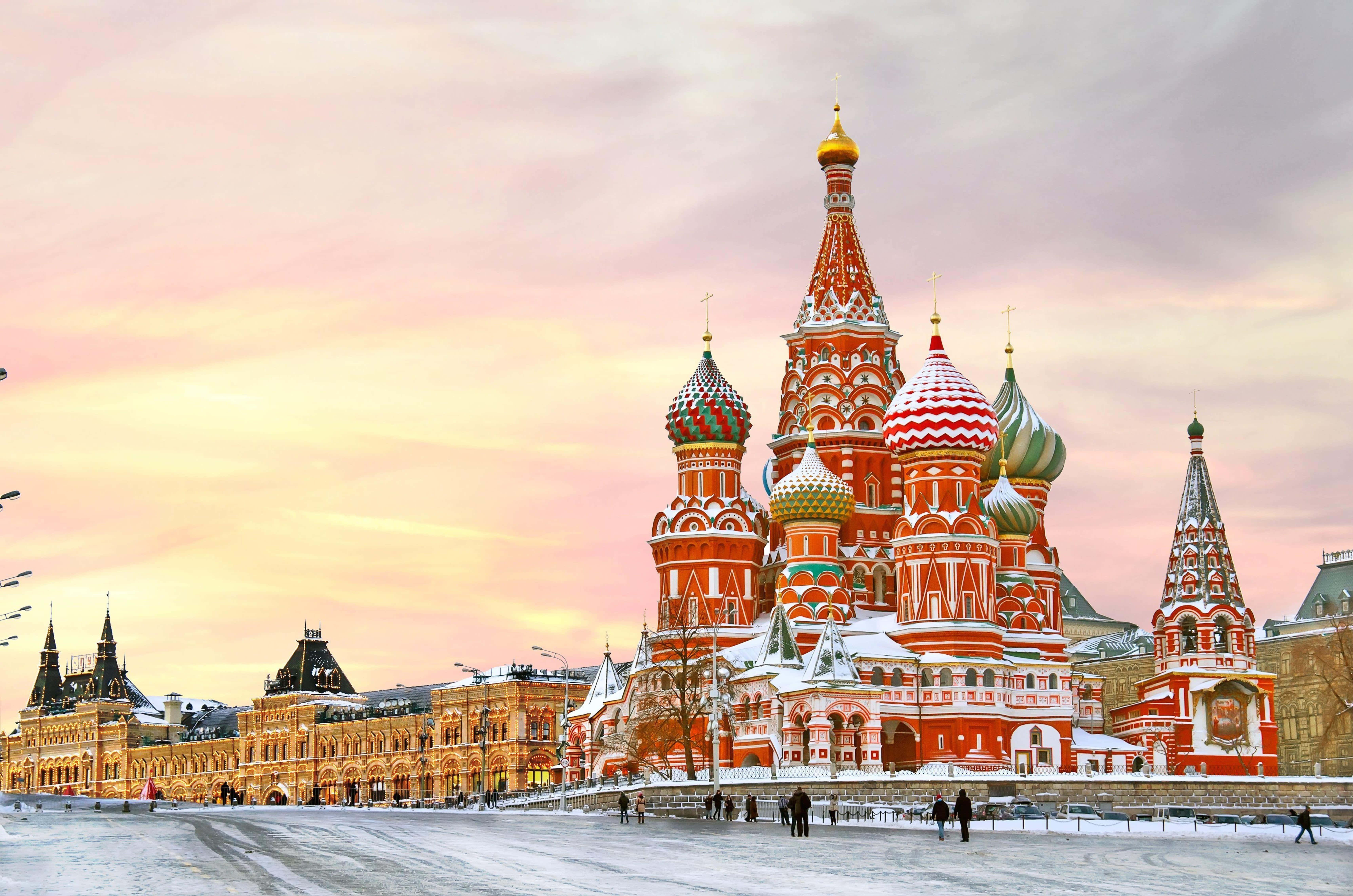 Russia 桌布 壁紙 — 莫斯科聖巴西爾大教堂在柔和粉紅與金色的日落天空下閃耀，白雪覆蓋地面。