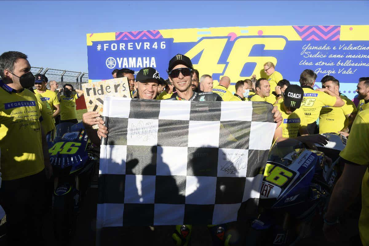 Chequered Flag 桌布 壁紙 — 華倫天奴·羅斯在燦爛陽光下與舉著格子旗的粉絲和車隊慶祝勝利。