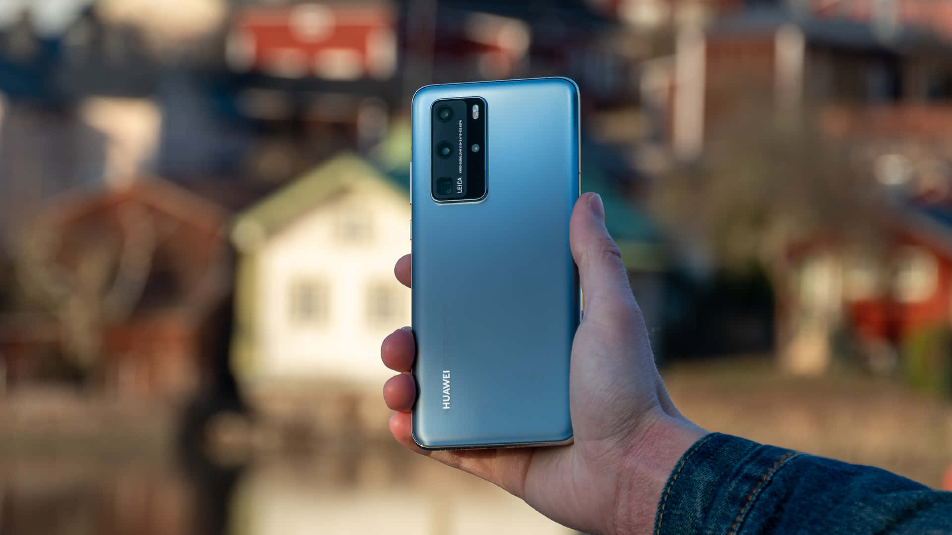 手拿著藍色Huawei智能手機，相機模組可見。
