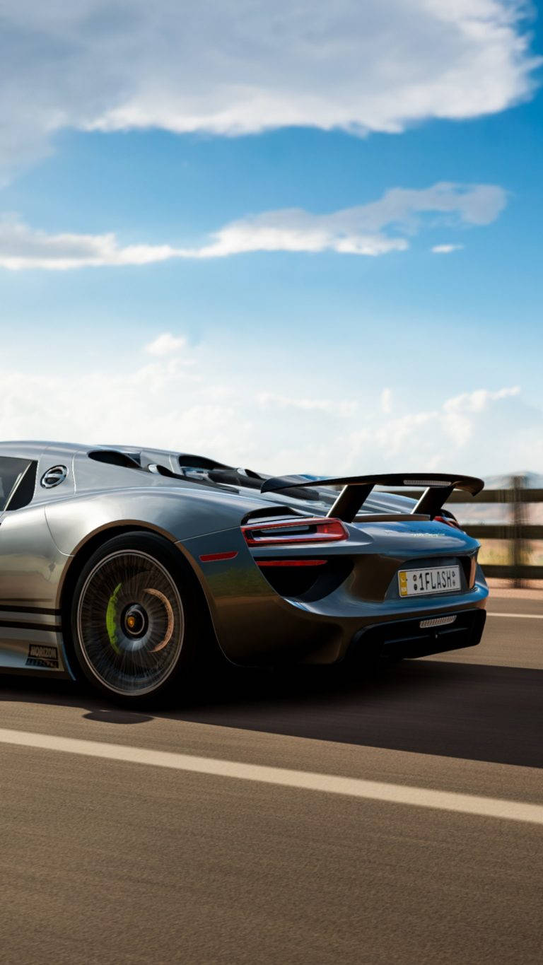 銀色保時捷918 Spyder在日落時分的道路上疾馳。