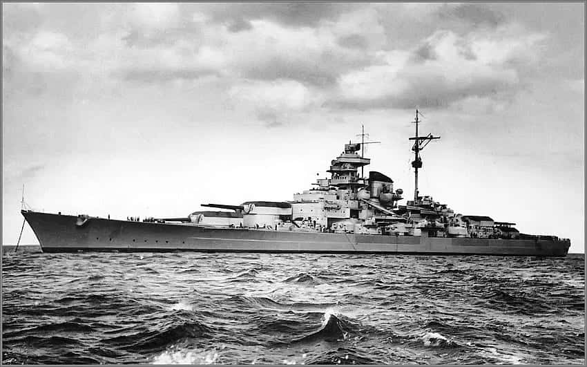 一艘巨大的戰艦在多雲的天空下於波濤洶湧的海上航行。