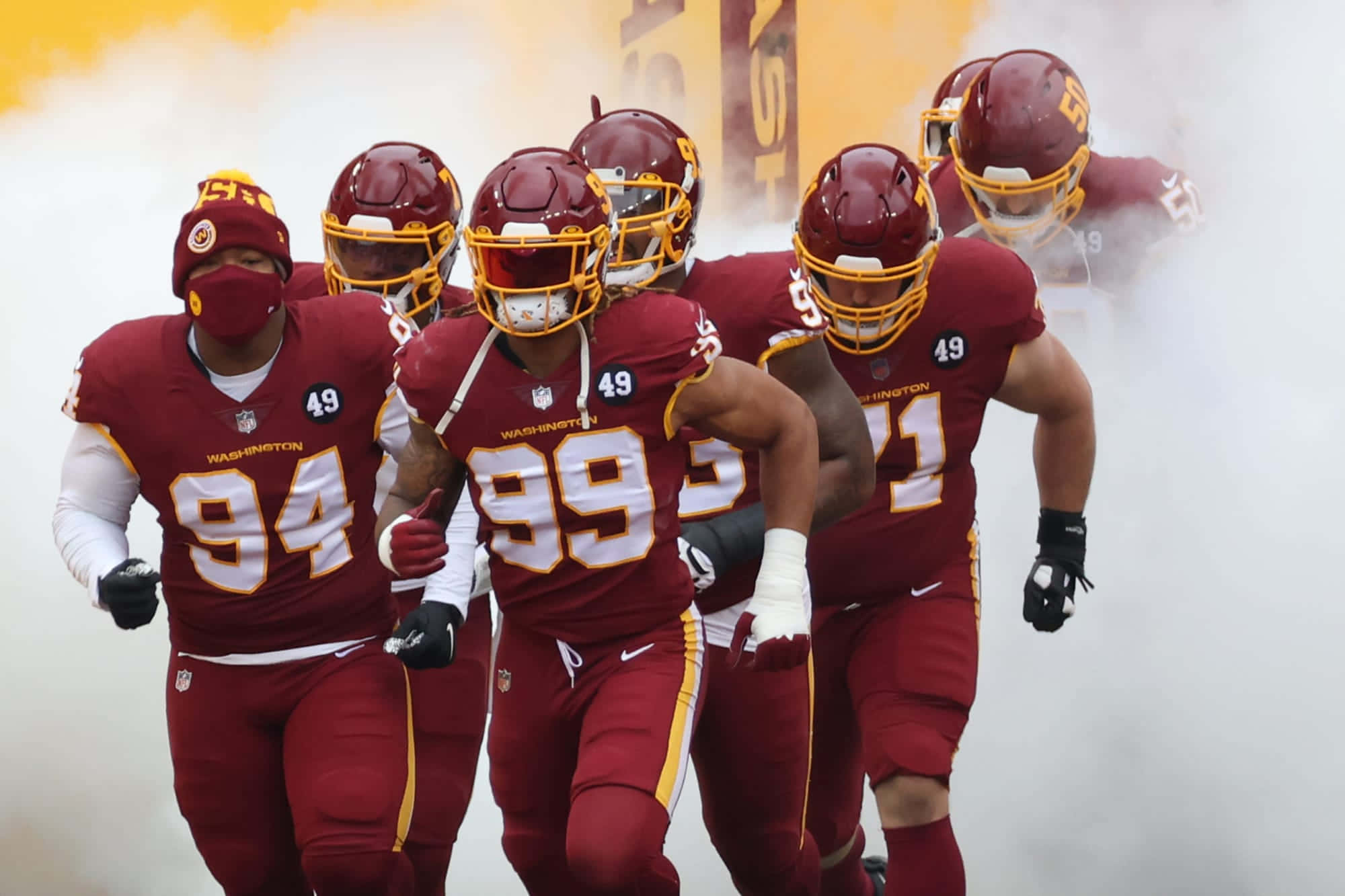 Washington Football 桌布 壁紙 — 華盛頓美式足球隊球員穿著栗色制服在比賽時間衝過煙霧瀰漫的隧道。