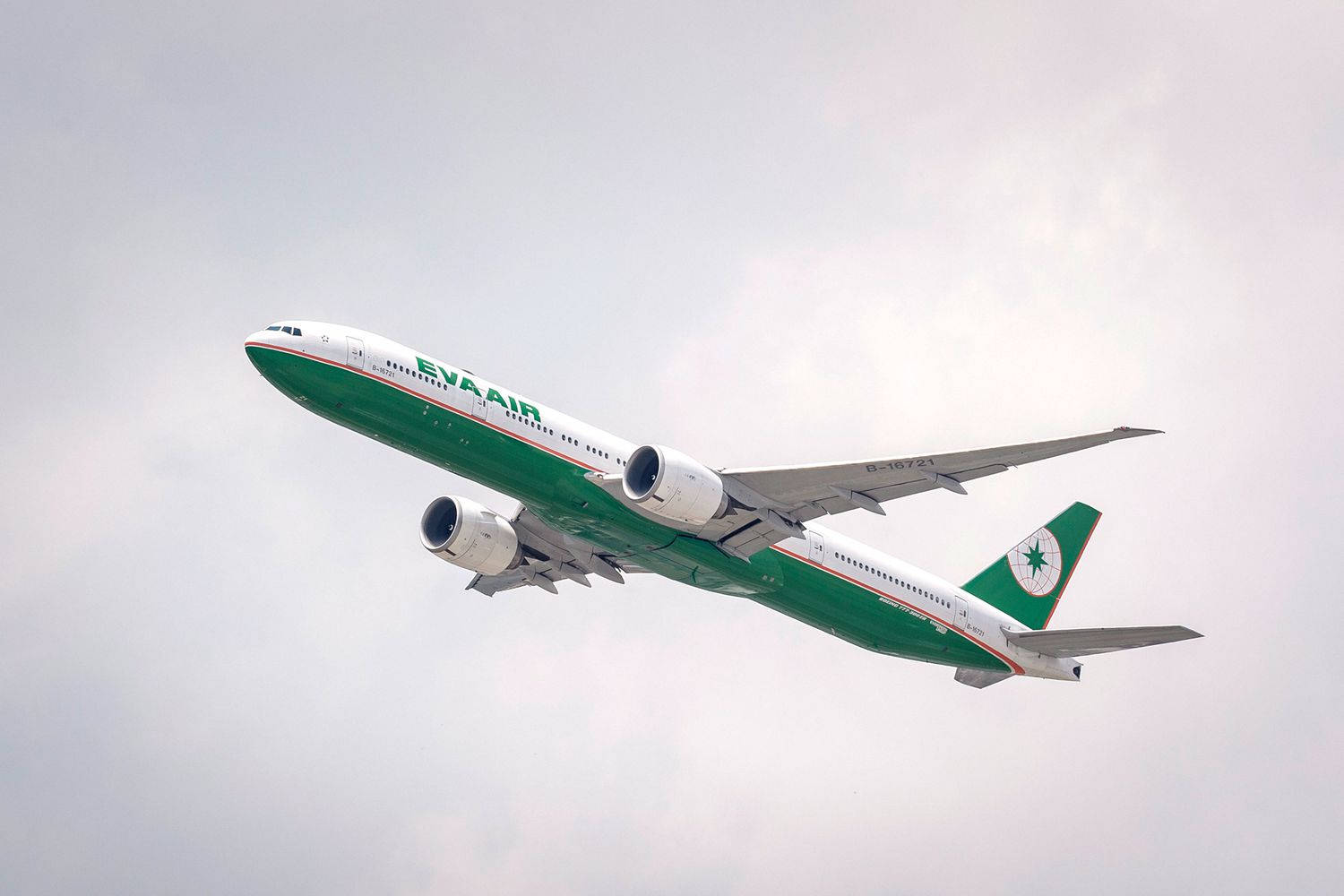 綠色和白色的長榮航空飛機在雲霧天空飛行。