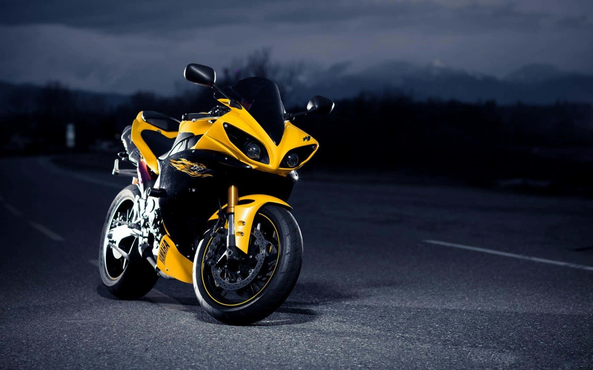 華麗Yamaha R系列機車背景 壁紙 — 一架搶眼的黃黑配色運動電單車，在陰沉的暮色天空下，停泊在空無一人的道路上。