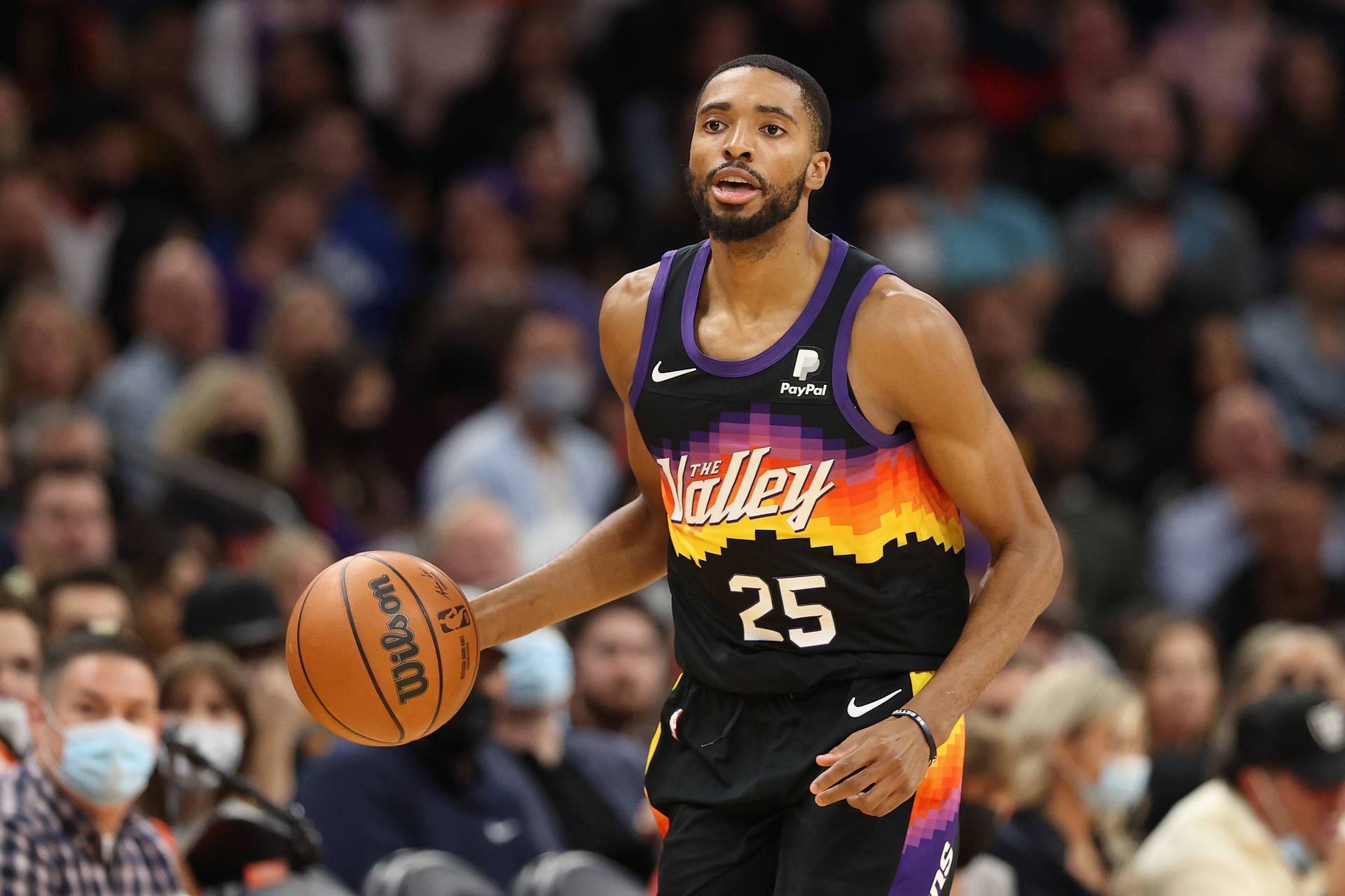 菲尼克斯太陽隊「The Valley」米卡爾·布里奇斯 壁紙 — 一名身穿黑色和紫色Suns球衣的籃球運動員在比賽中運球，背景是模糊的人群。