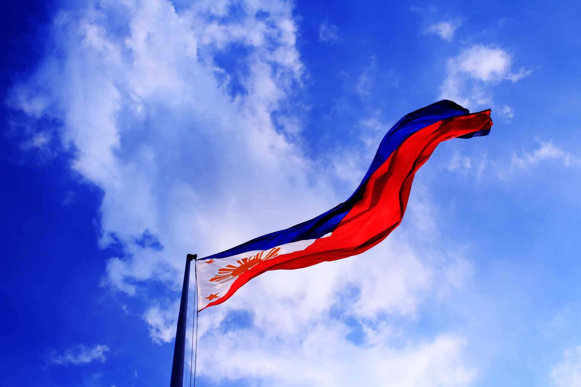 Philippines 桌布 壁紙 — 菲律賓國旗在點綴著蓬鬆白雲的鮮豔藍天下動態飄揚。