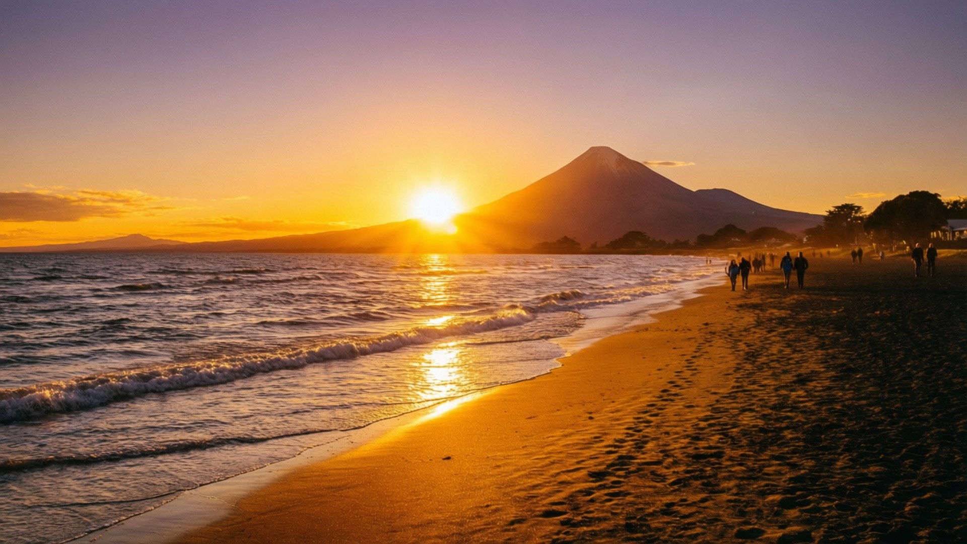 人們在金色夕陽下沿著海灘漫步，背景是山脈。