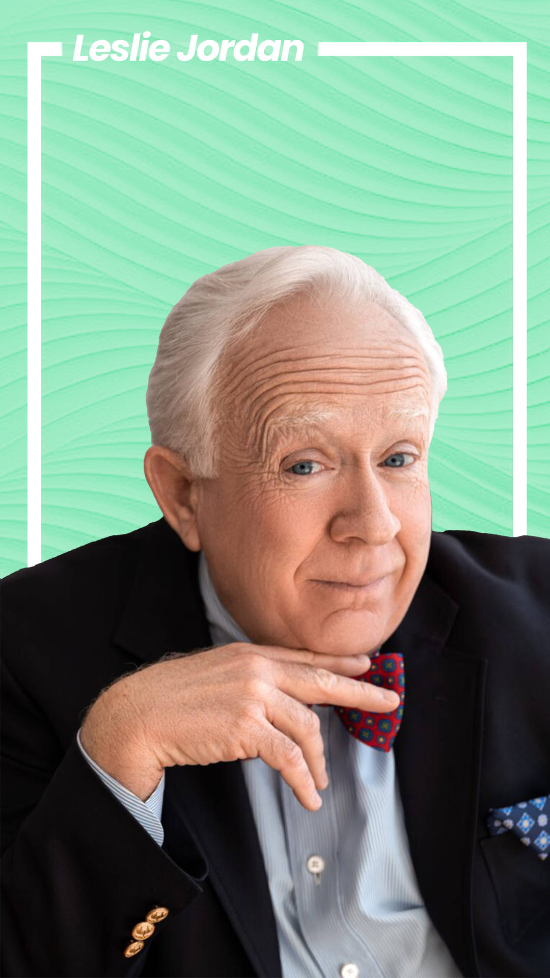 Leslie Jordan 身穿西裝打領結，背景為藍綠色。