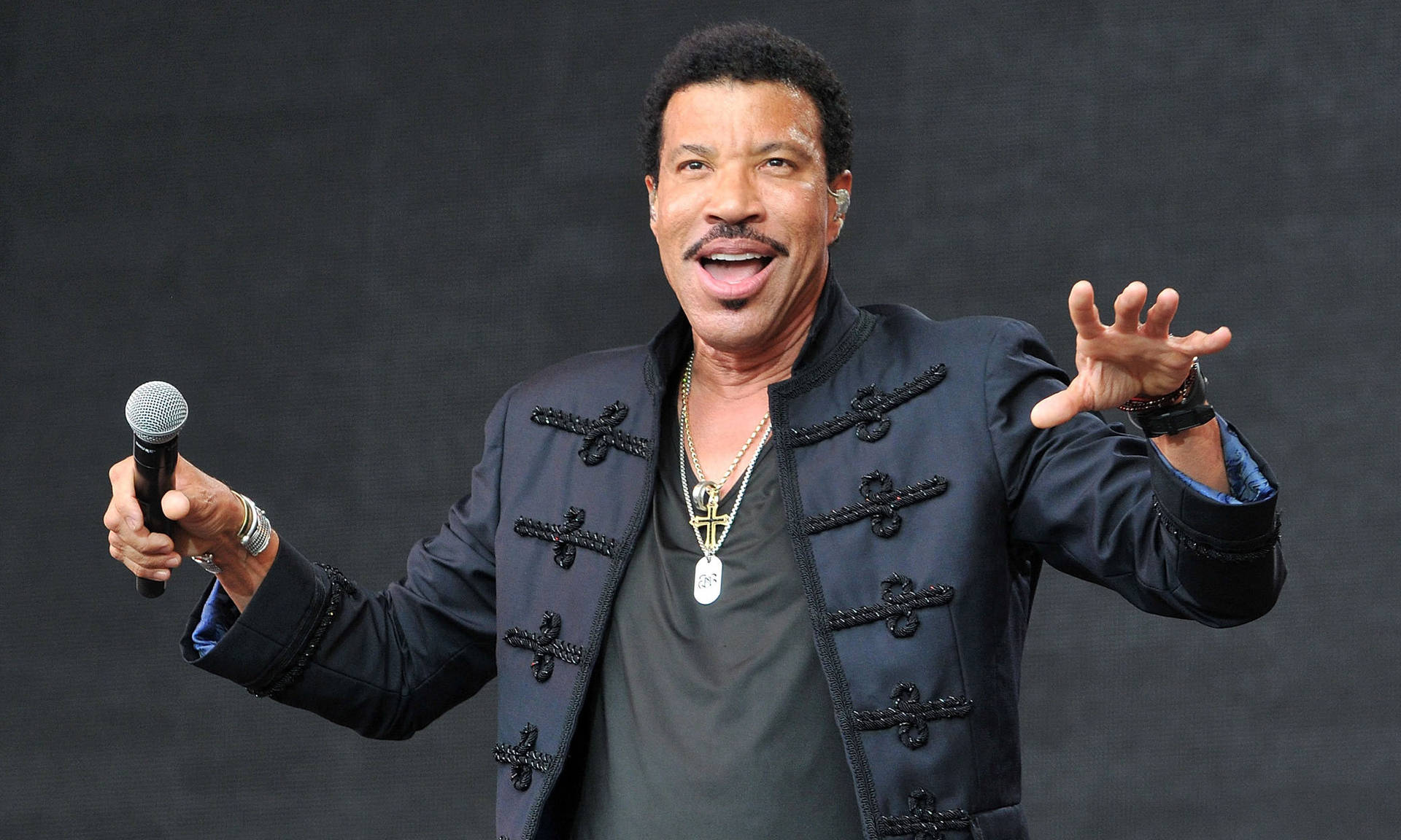 Lionel Richie 在舞台上用咪高峰唱歌，表情豐富。