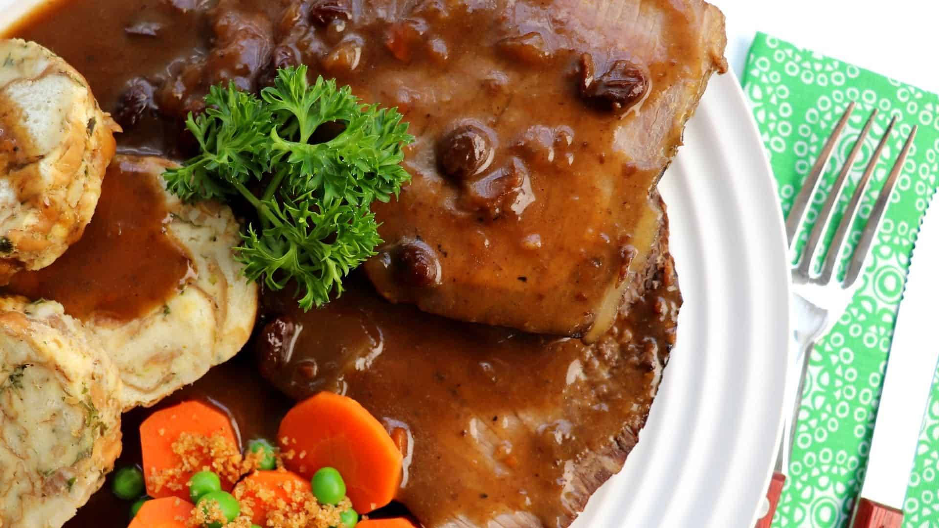 肉餅配肉汁、薯蓉、紅蘿蔔、豌豆和歐芹裝飾，放在白色盤子上。