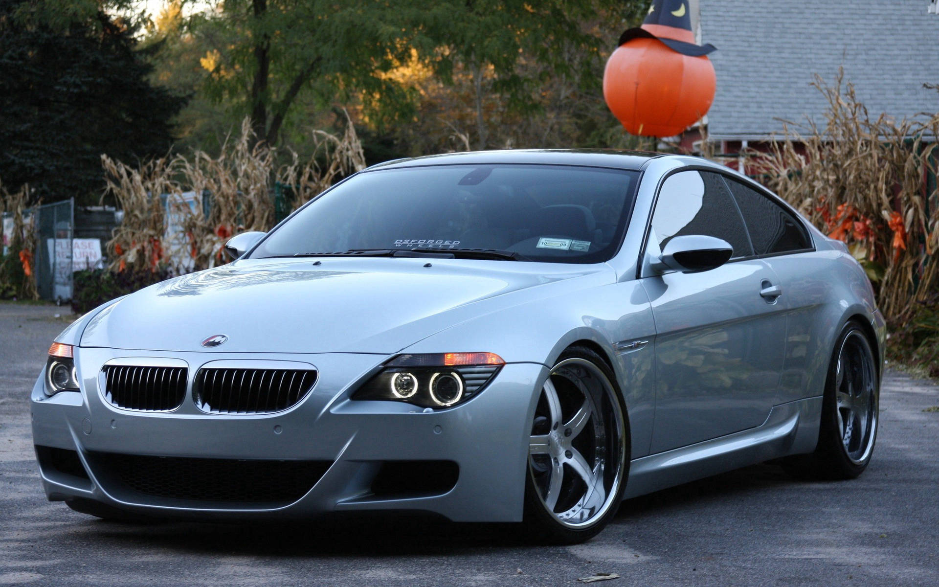 銀色BMW M6跑車在秋天停泊在萬聖節裝飾附近。