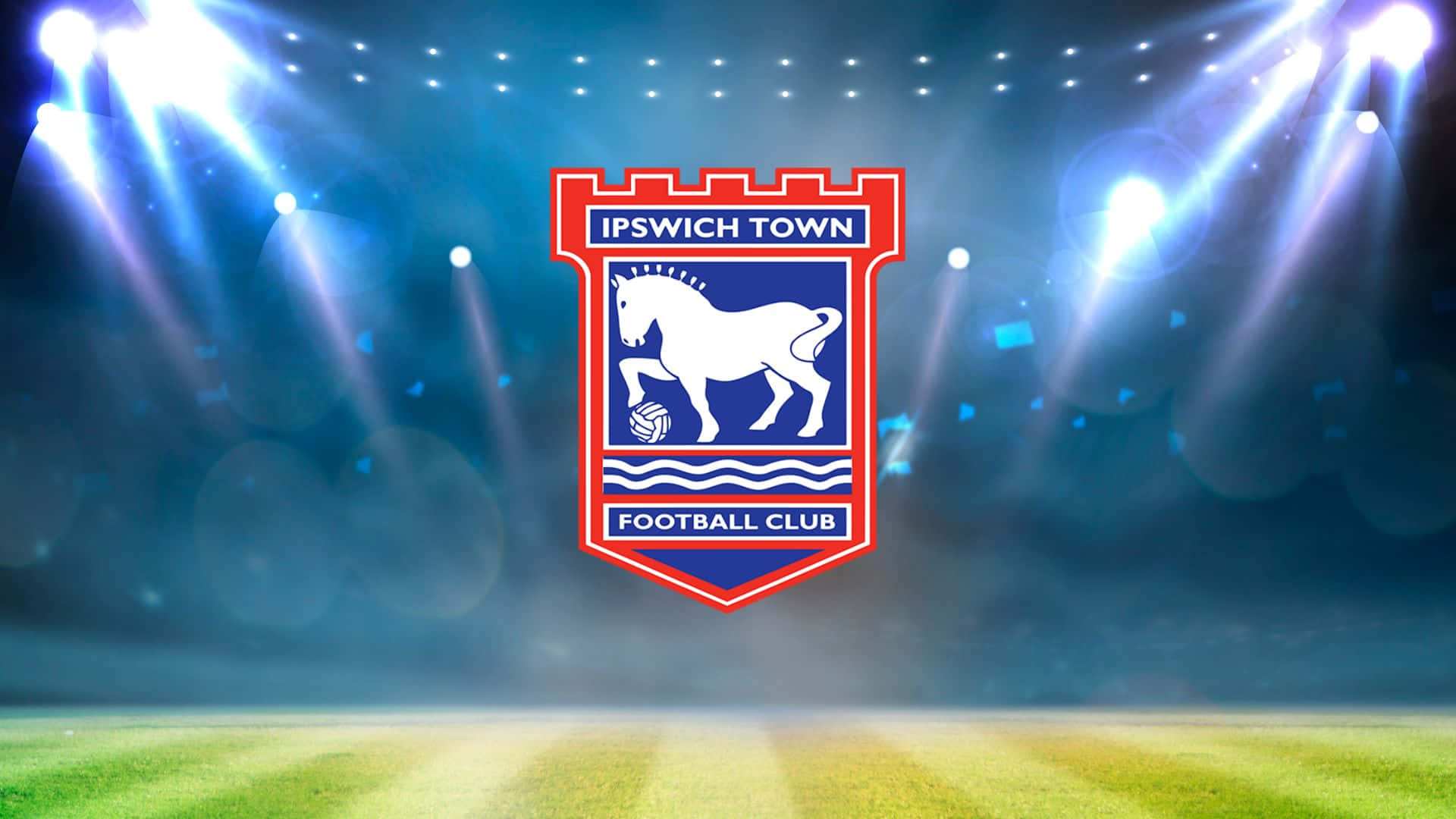 Ipswich Town 桌布 壁紙 — 葉士域治足球會徽章在充滿活力的綠色球場上被球場聚光燈照亮。