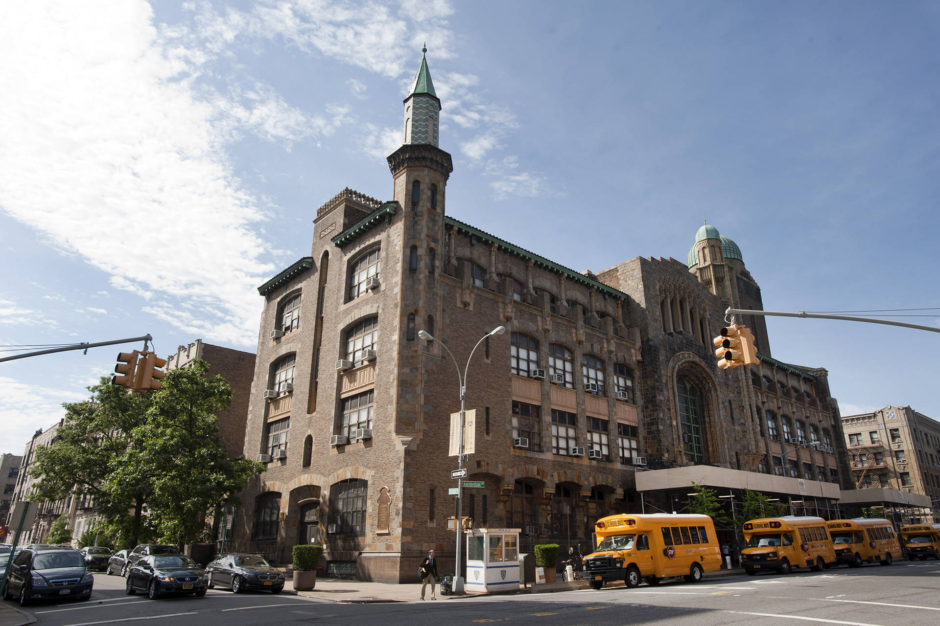 歷史石建築，帶有綠色尖頂和城市街道上的黃色校車。