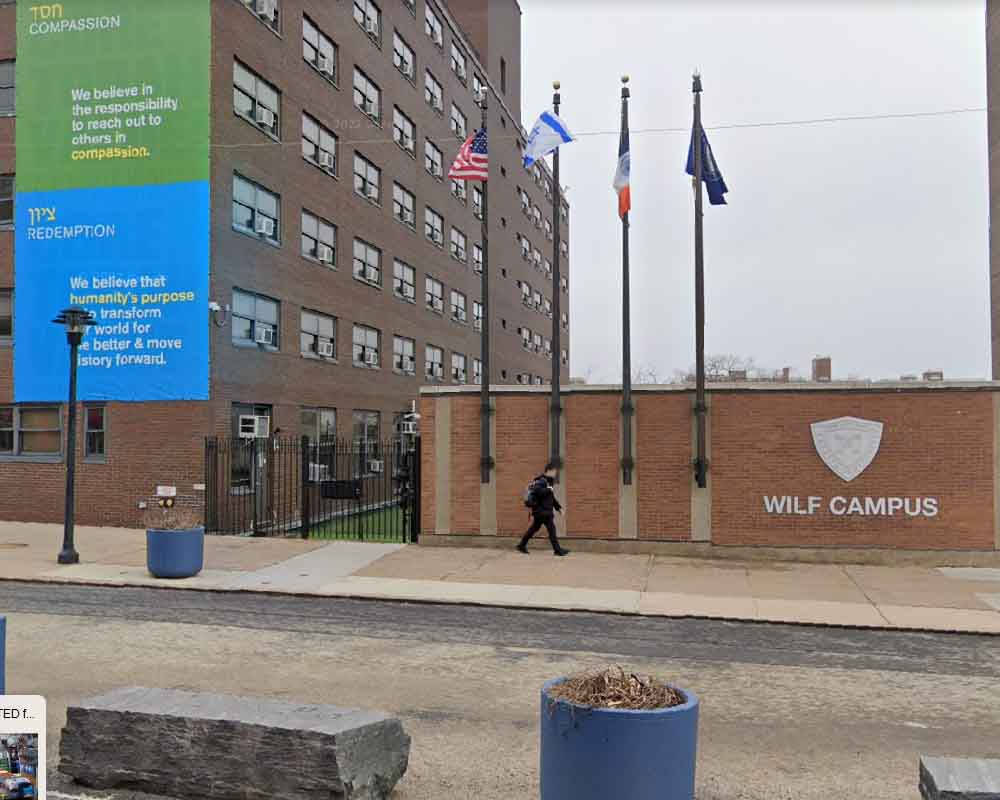 人走過 Wilf Campus 磚牆，帶有旗幟和標誌。