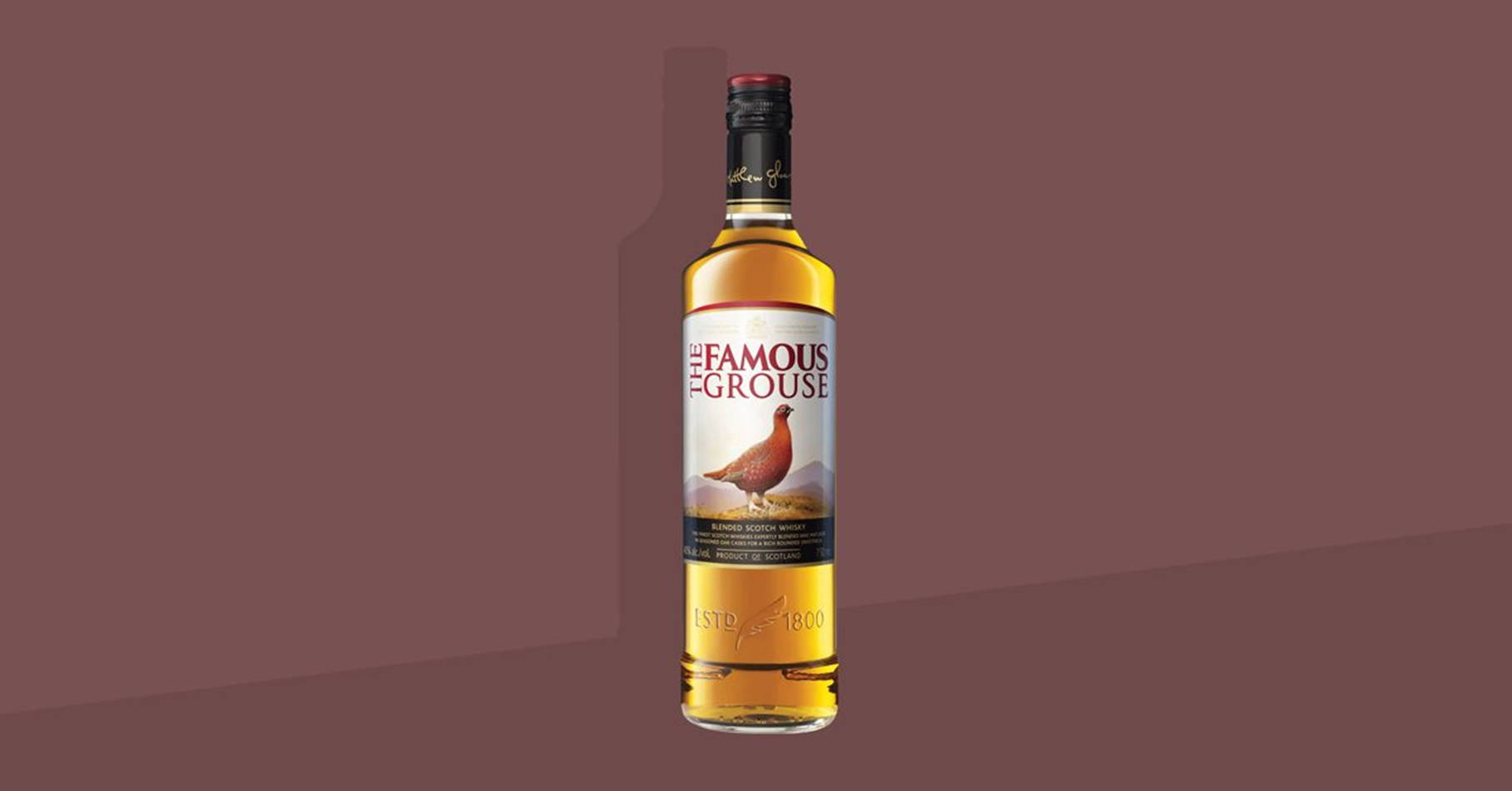 一瓶 The Famous Grouse 威士忌在栗色漸變背景上。