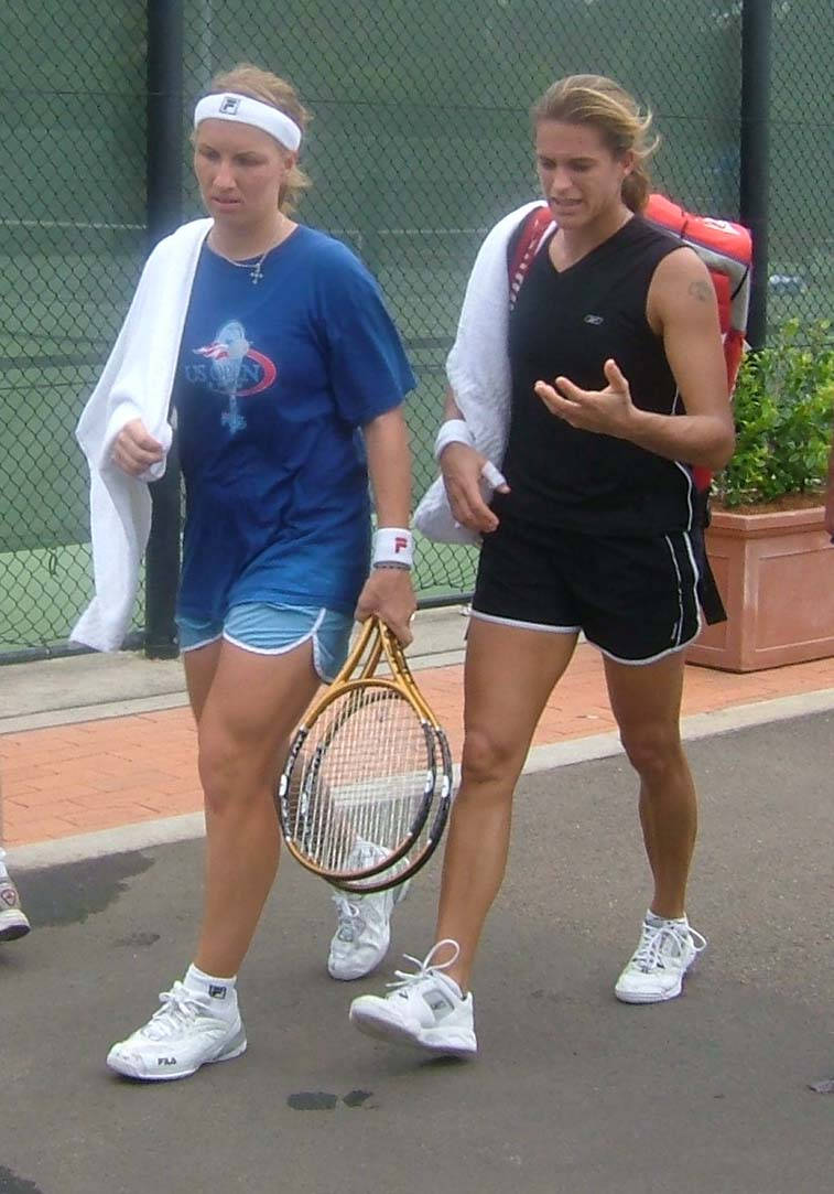 著名網球選手_světlana_kuznetsova_與_amelie_mauresmo_比賽瞬間 壁紙 — 兩名身穿運動裝備的女網球手在球場旁邊行走，一人拿著球拍，另一人正在交談中做手勢。