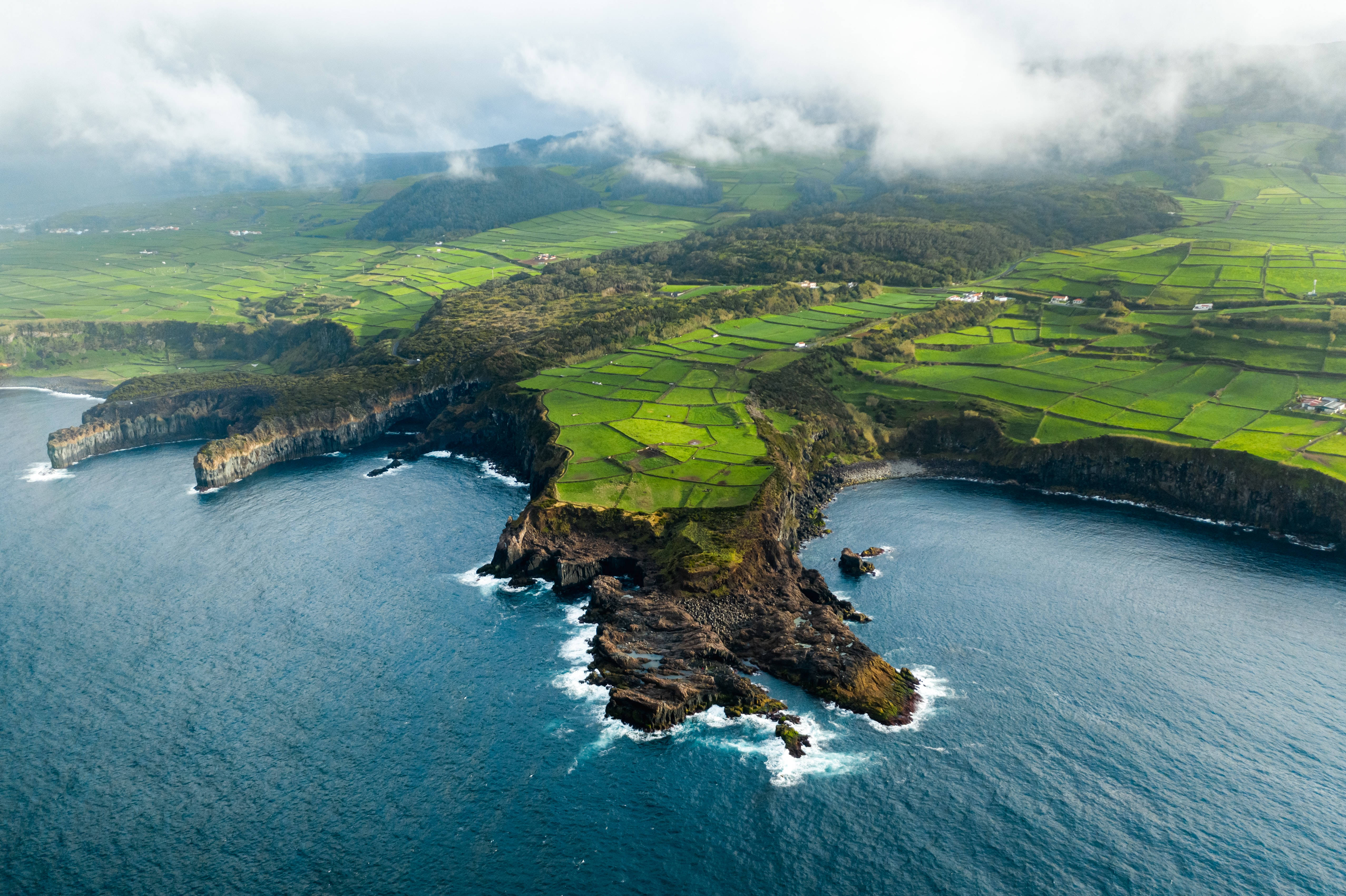 葡萄牙亞速爾群島 壁紙 — 鳥瞰圖：鬱鬱蔥蔥的梯田山丘與崎嶇懸崖和深藍色海洋在陰天下交匯。