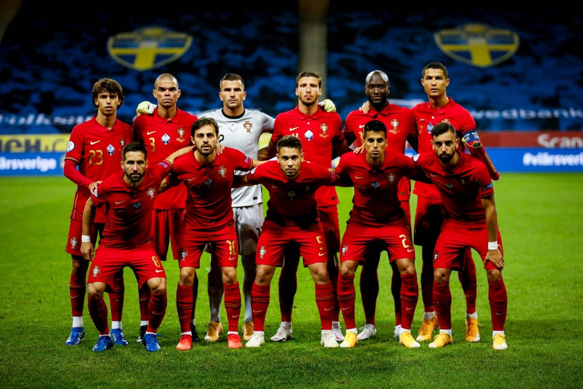 葡萄牙國家足球隊FIFA世界盃官方集體照 壁紙 — 葡萄牙國家足球隊身穿紅色球衣，在體育場燈光下自信地站在充滿活力的綠色球場上。